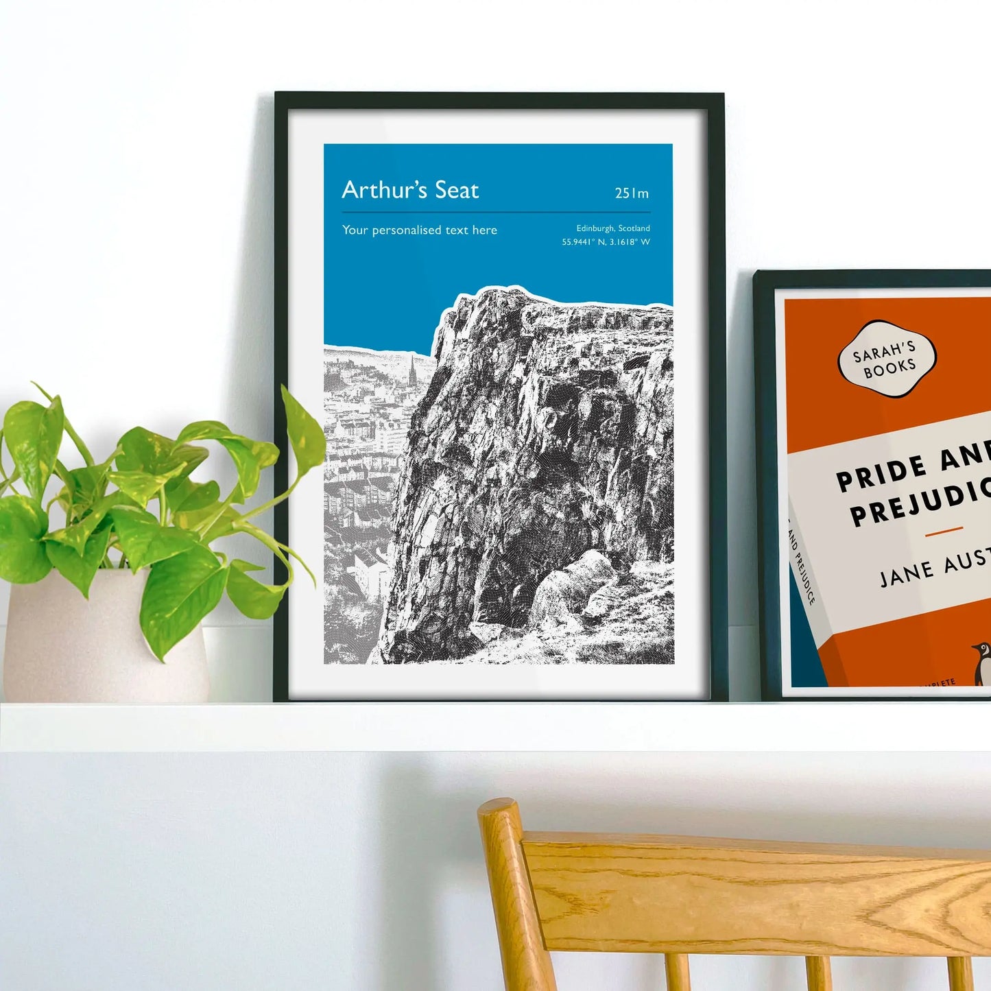 Framed picture on shelf beside a houseplant and another print.