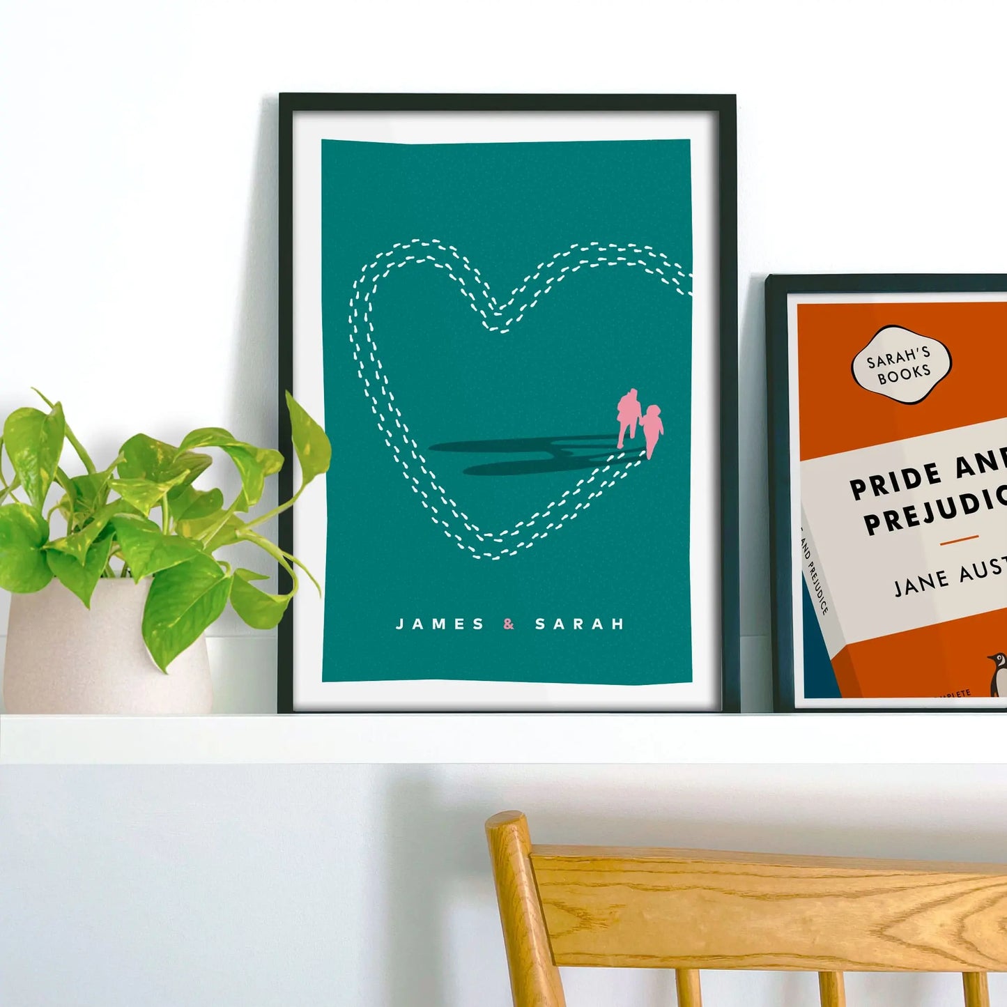 Framed picture on shelf beside a houseplant and another print.