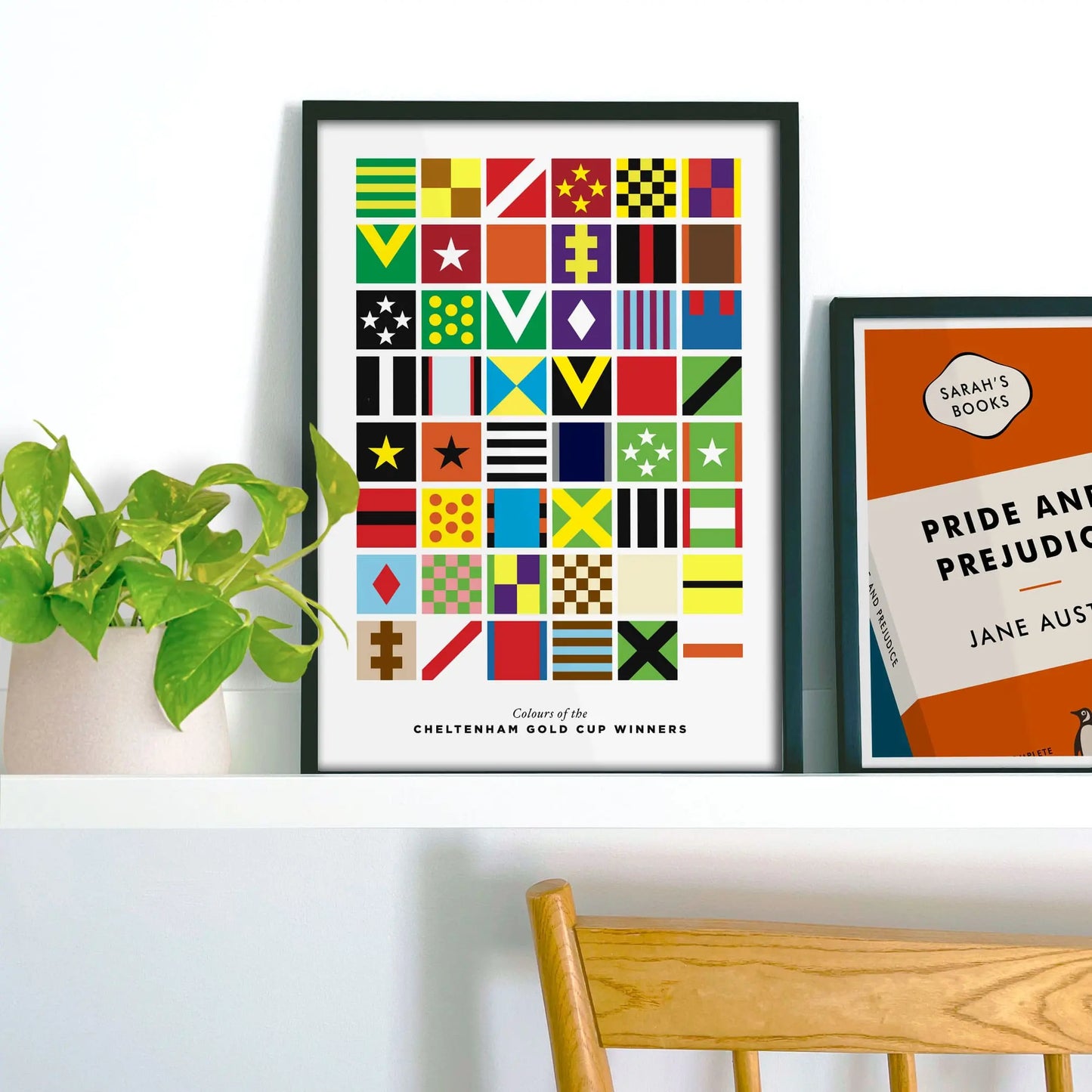 Framed picture on shelf beside a houseplant and another print.