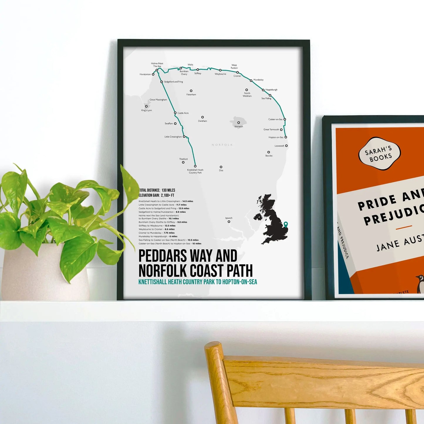 Framed picture on shelf beside a houseplant and another print.