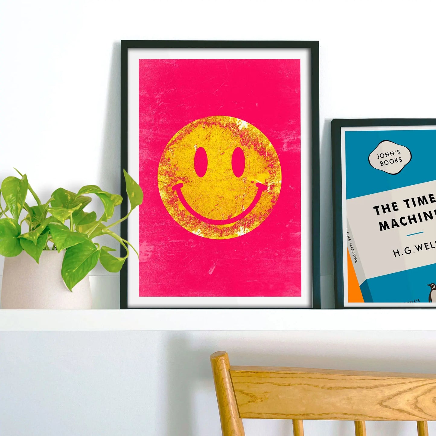 Framed picture on shelf beside a houseplant and another print.