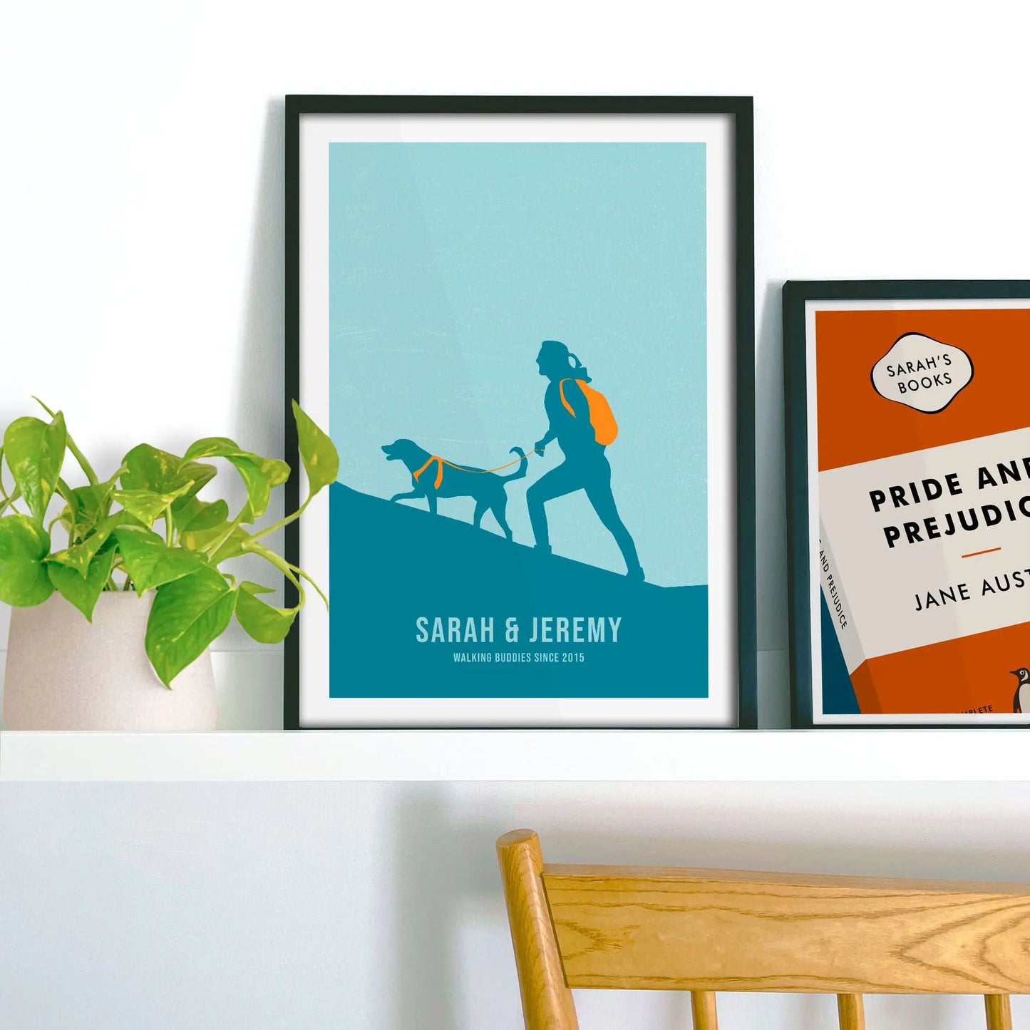 Framed print propped up on shelf beside a houseplant