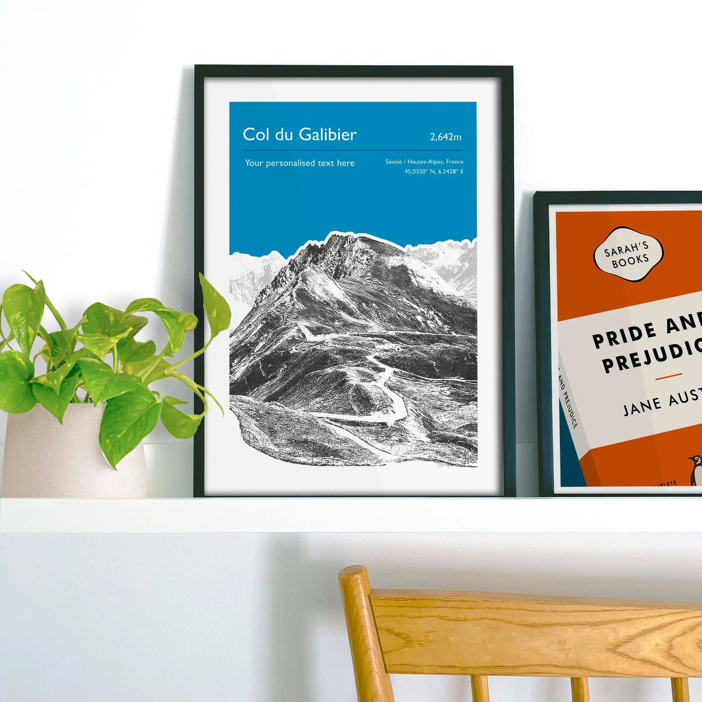 Framed picture on shelf beside a houseplant and another print.