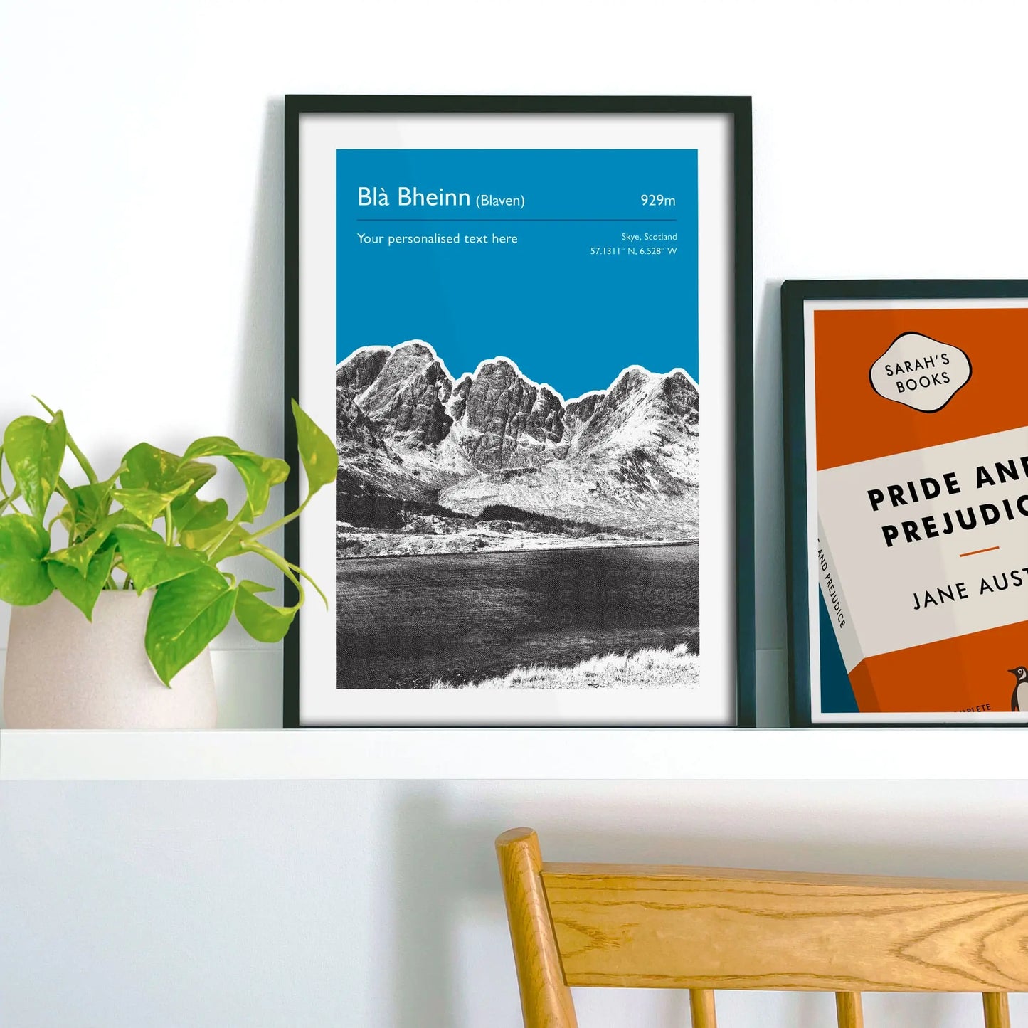 Framed picture on shelf beside a houseplant and another print.