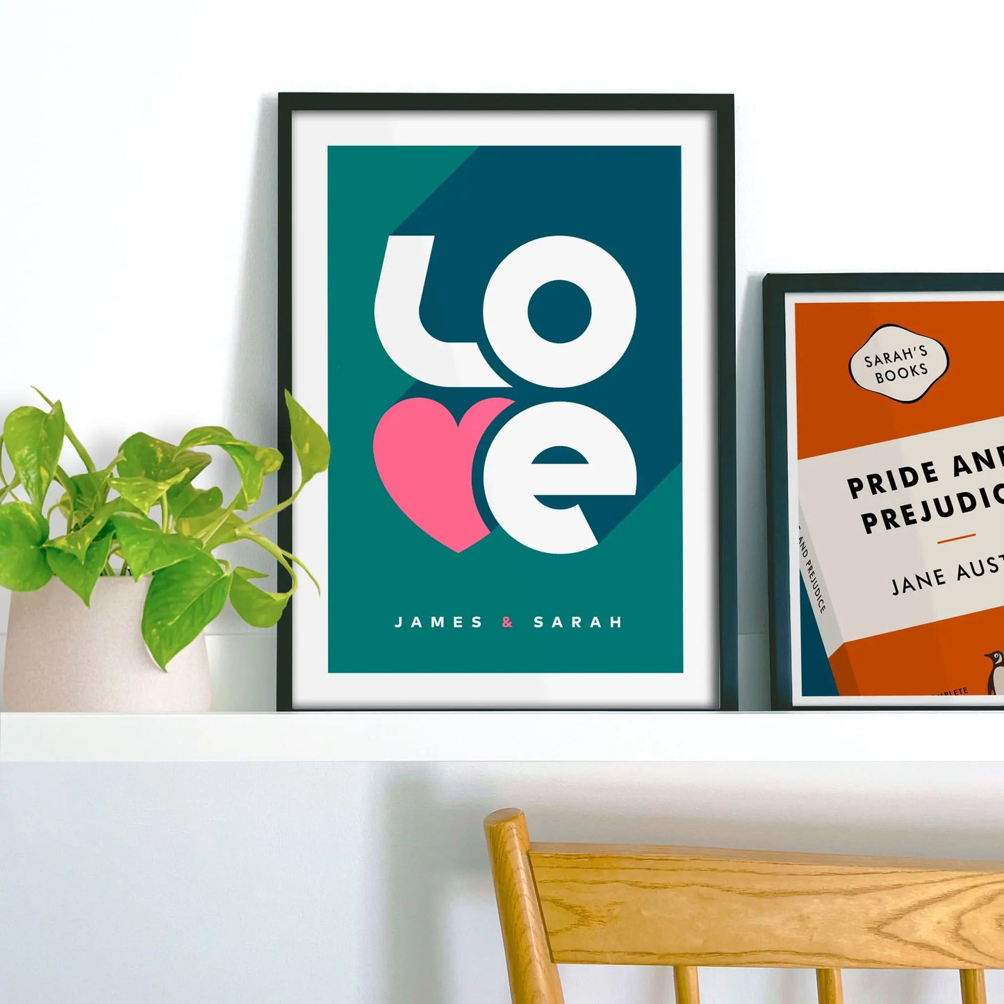 Framed picture on shelf beside a houseplant and another print.