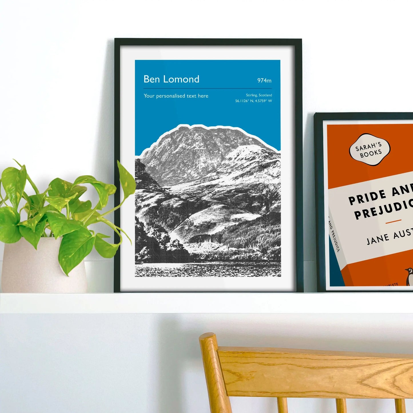 Framed picture on shelf beside a houseplant and another print.