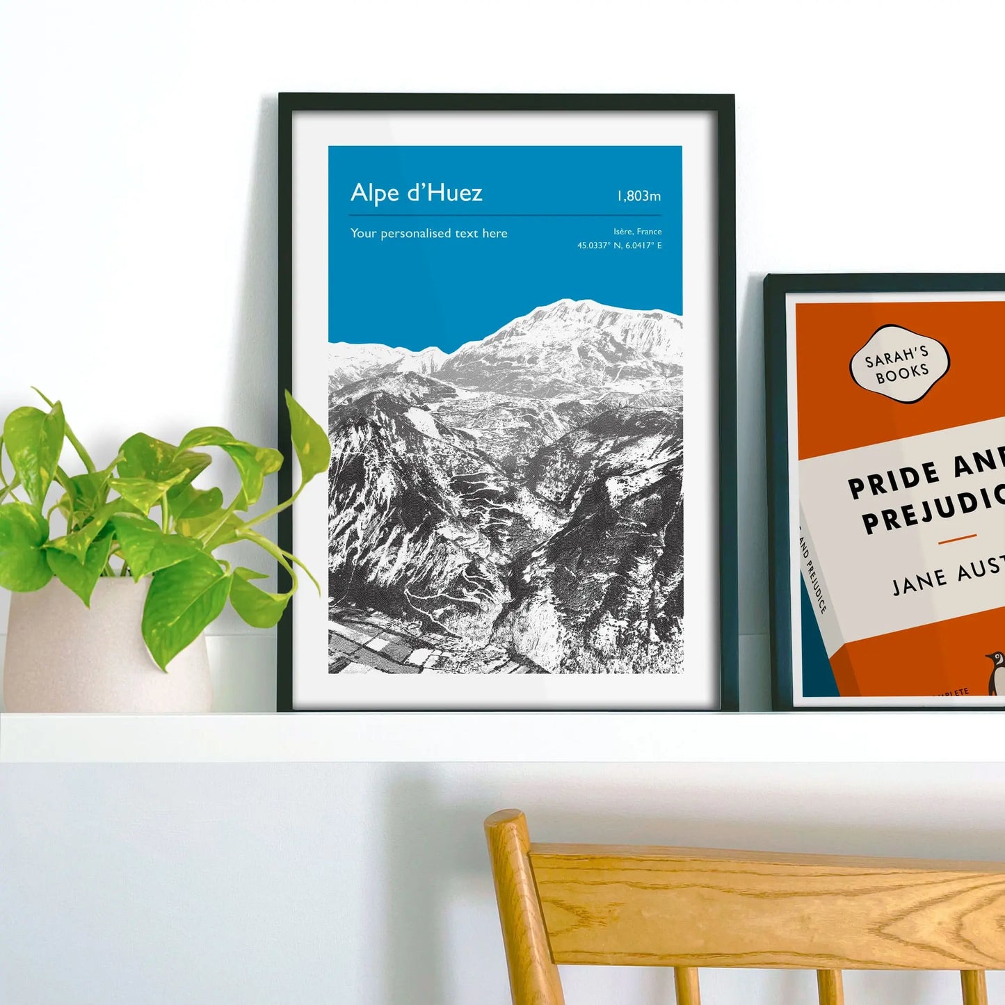 Framed picture on shelf beside a houseplant and another print.