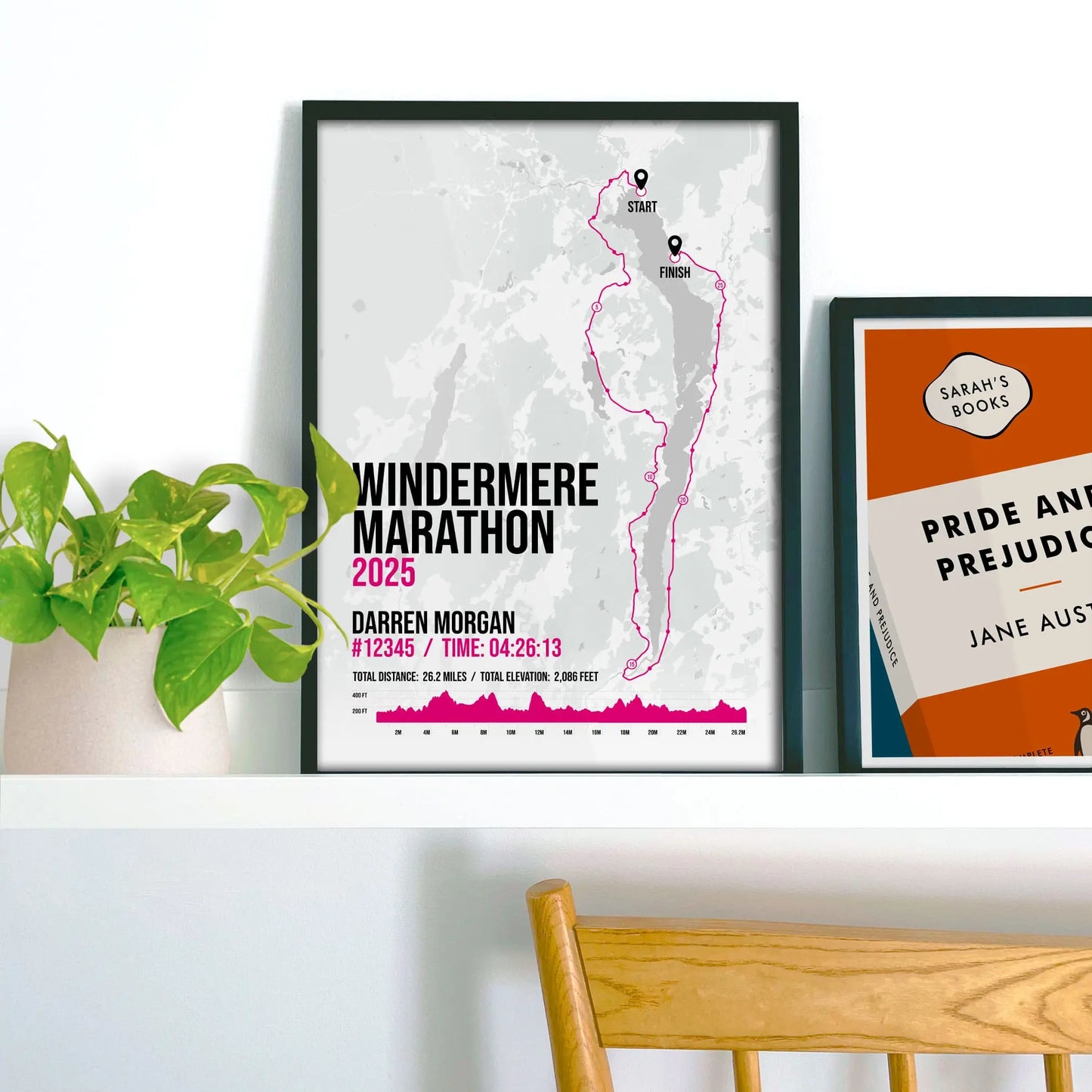 Framed print on shelf beside a houseplant and another smaller print.