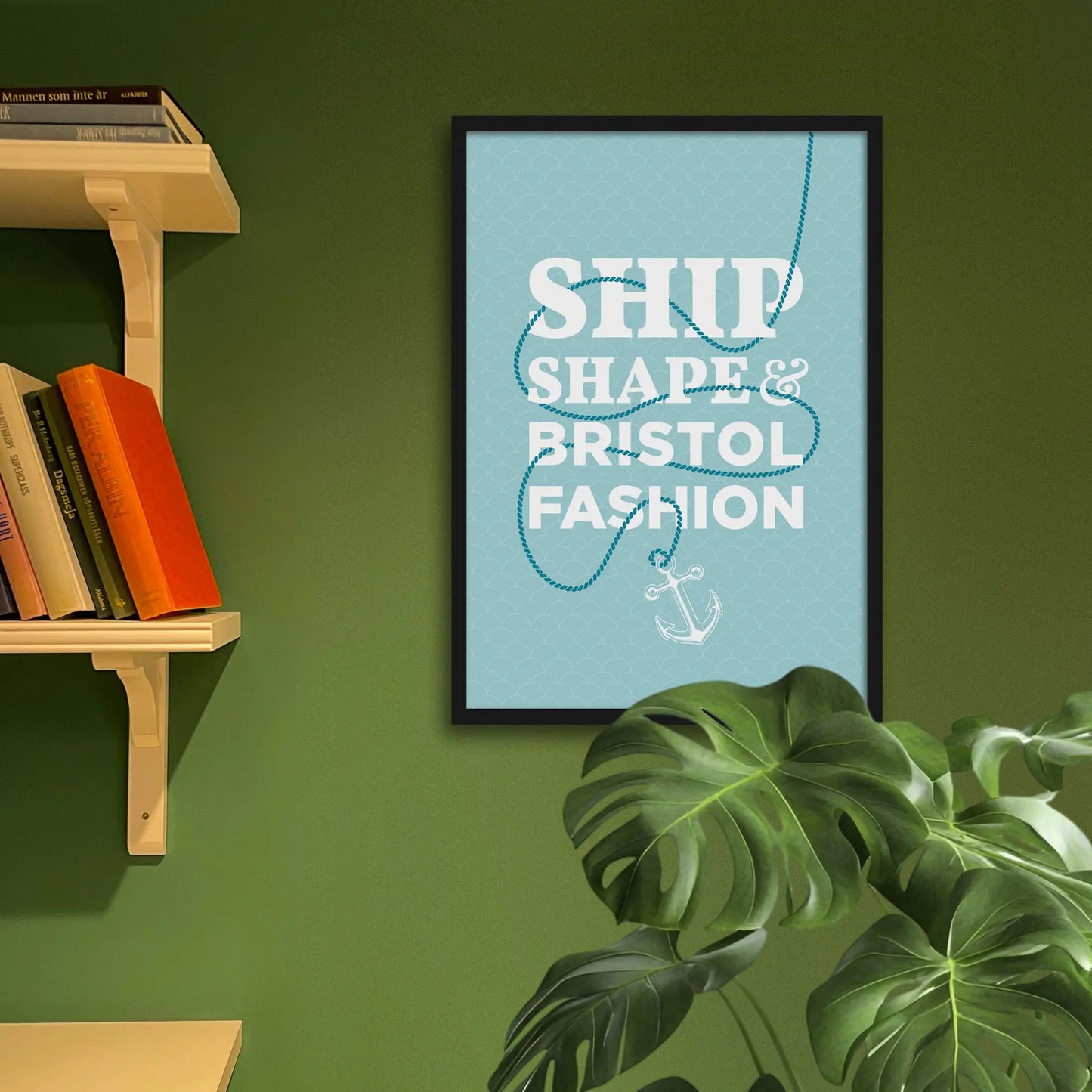 Framed art print on a green wall beside shelves.