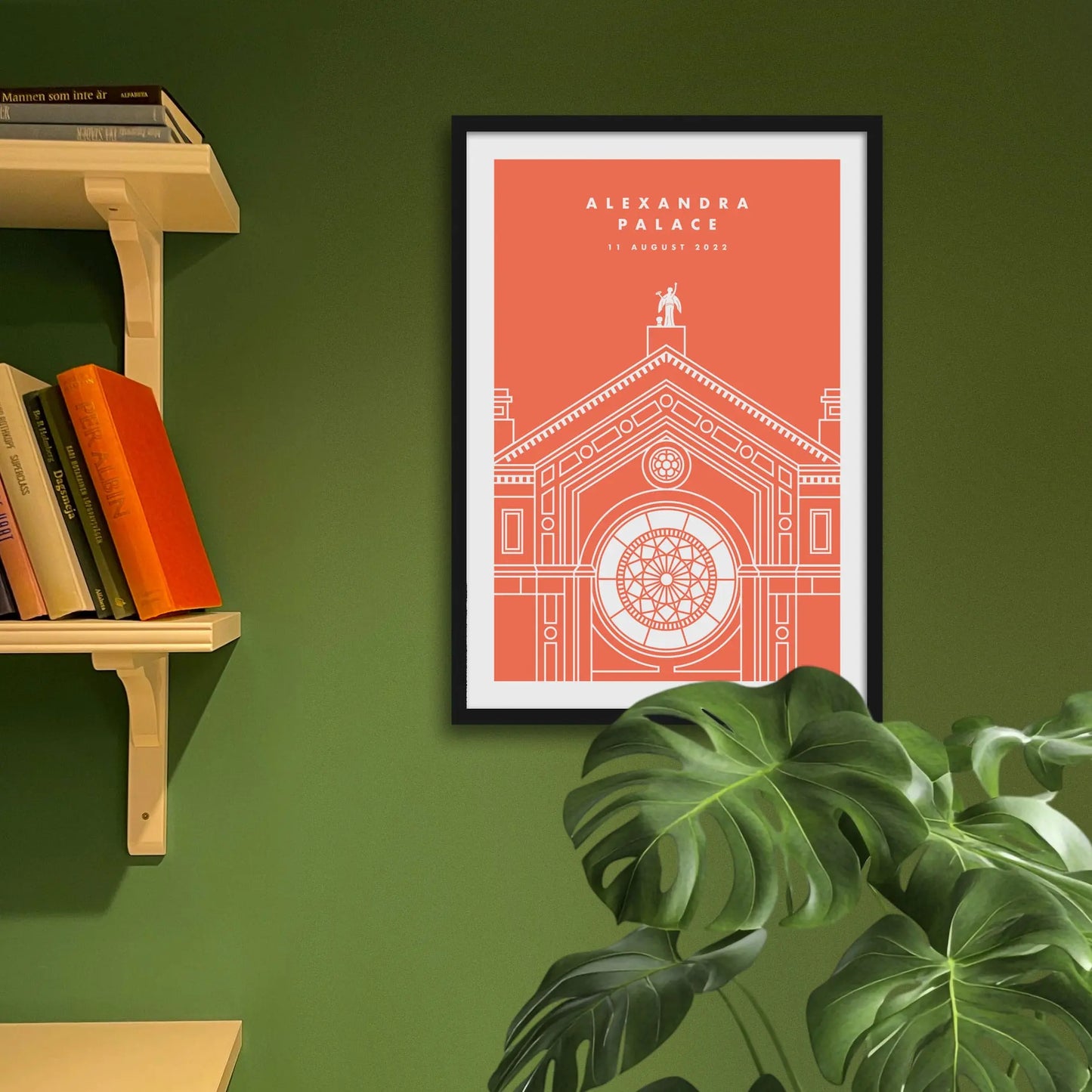 Framed art print on a green wall beside shelves.