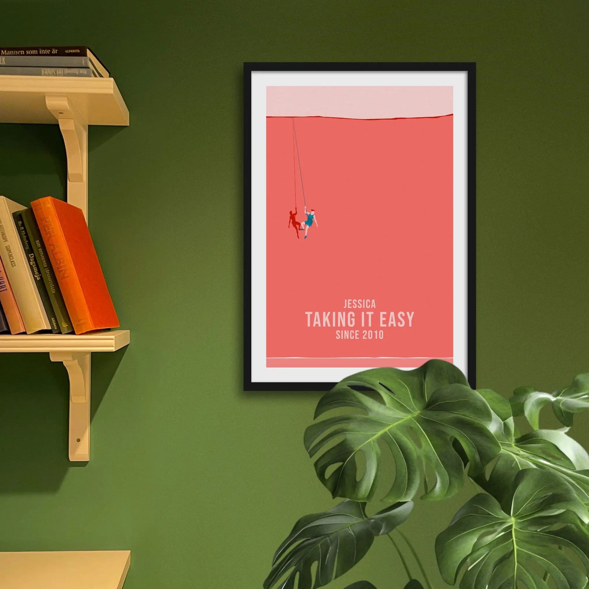 Framed print on green wall beside shelves behind houseplant.
