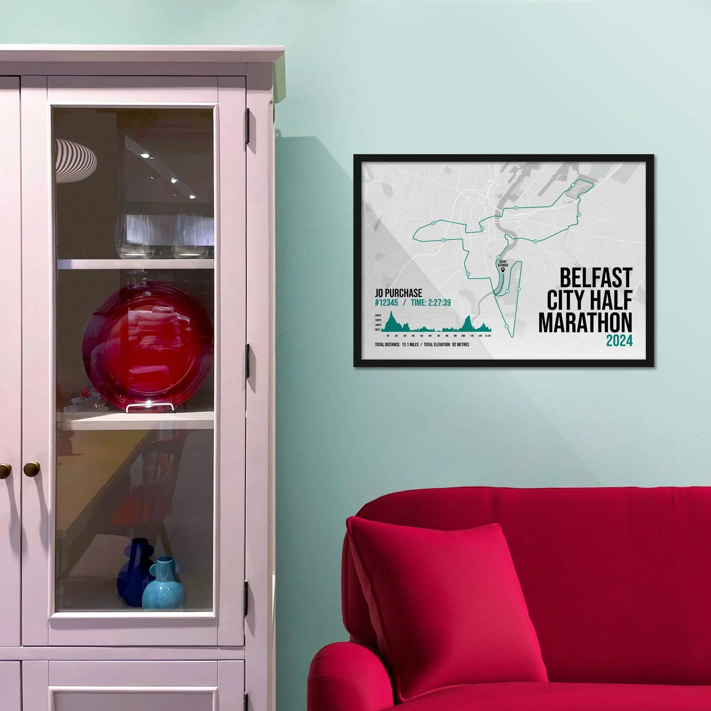 Framed picture on a baby blue wall beside pink shelving