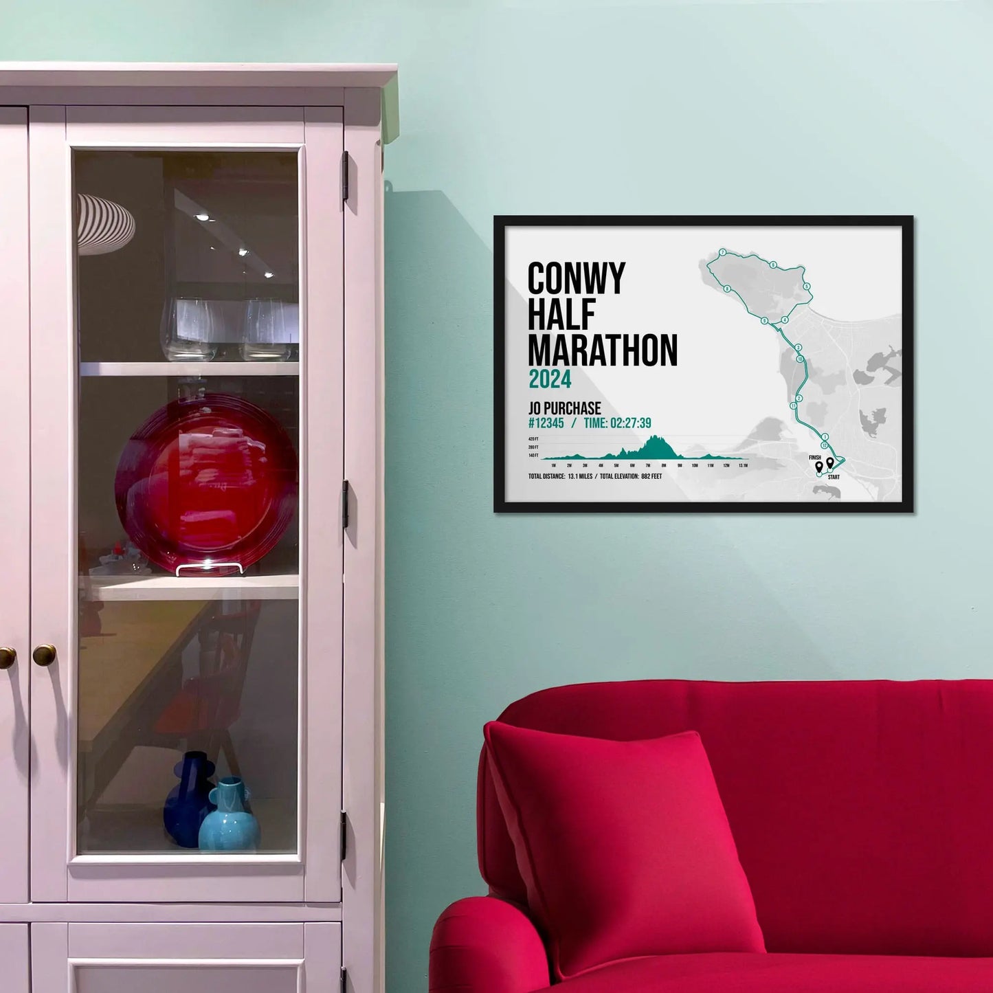 Framed picture on a baby blue wall beside pink shelving