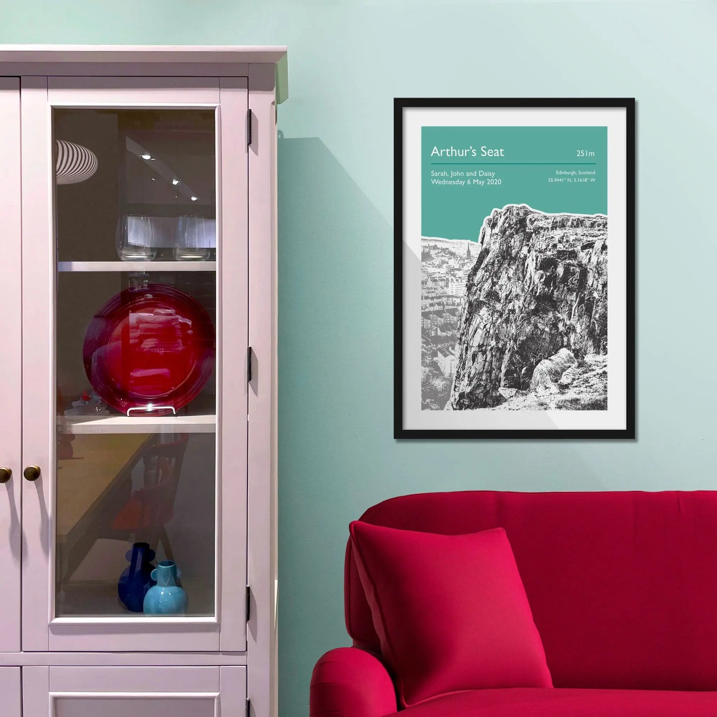 Framed picture on a baby blue wall beside pink shelving