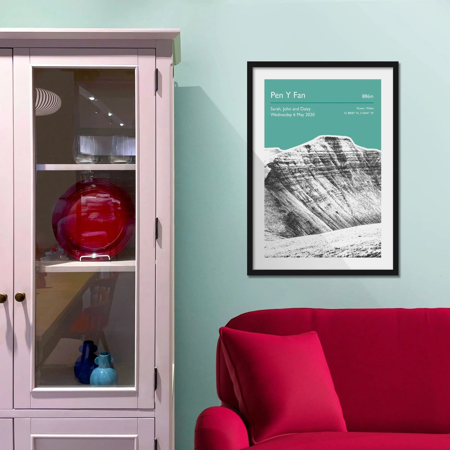 Framed picture on a baby blue wall beside pink shelving