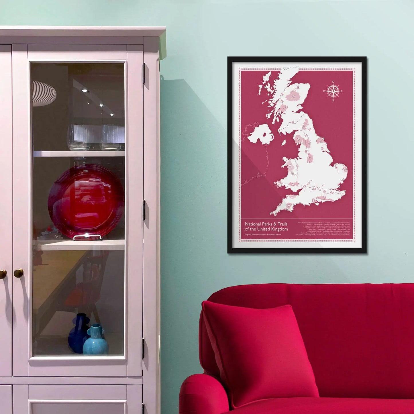 Framed picture on a baby blue wall beside pink shelving