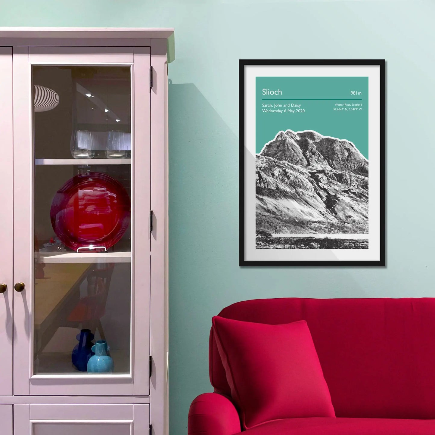 Framed picture on a baby blue wall beside pink shelving