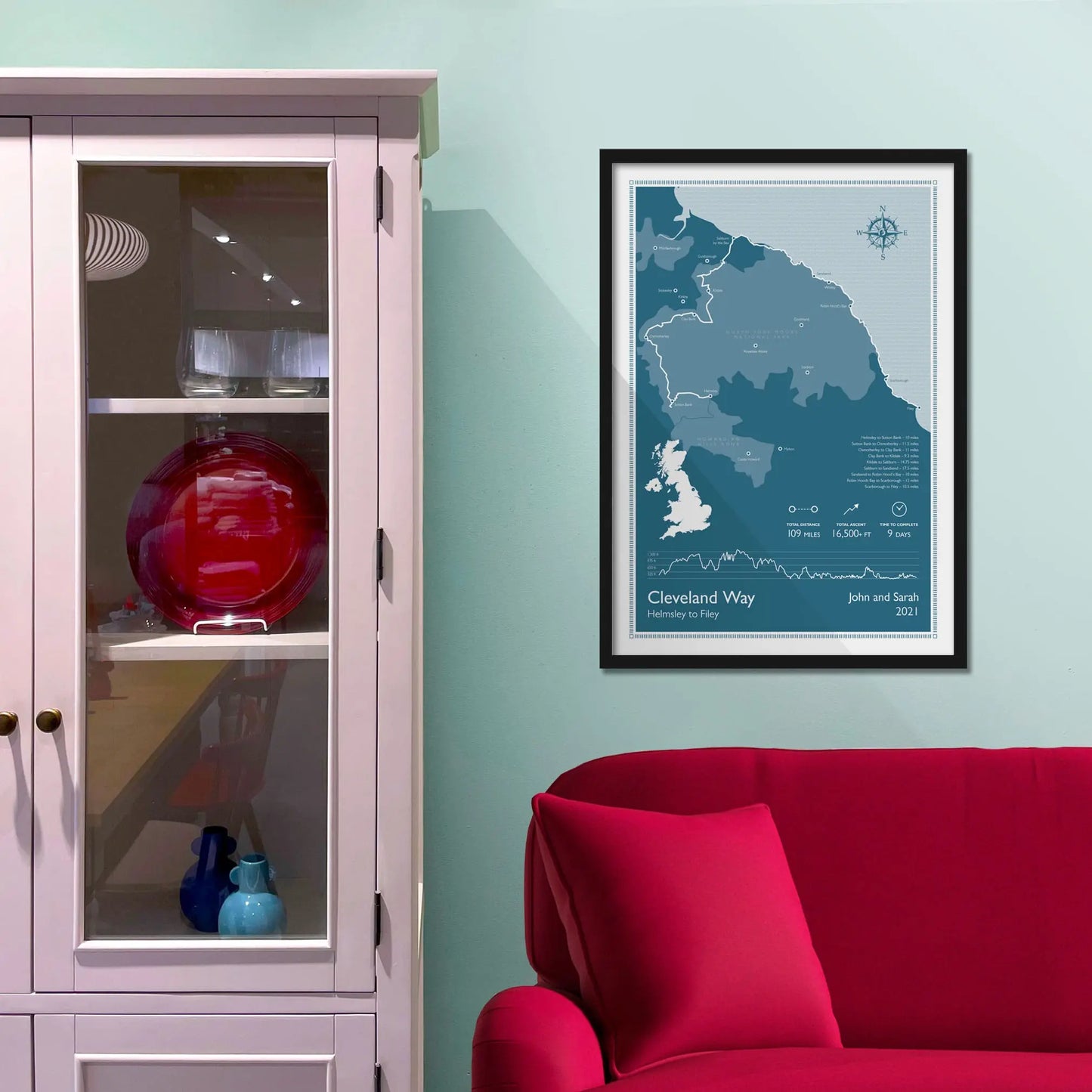 Framed picture on a baby blue wall beside pink shelving