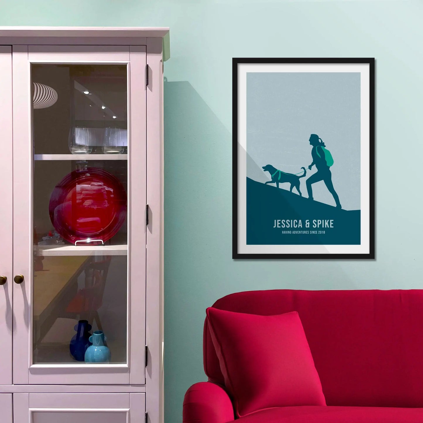 Framed print on light blue wall beside pink shelving unit.