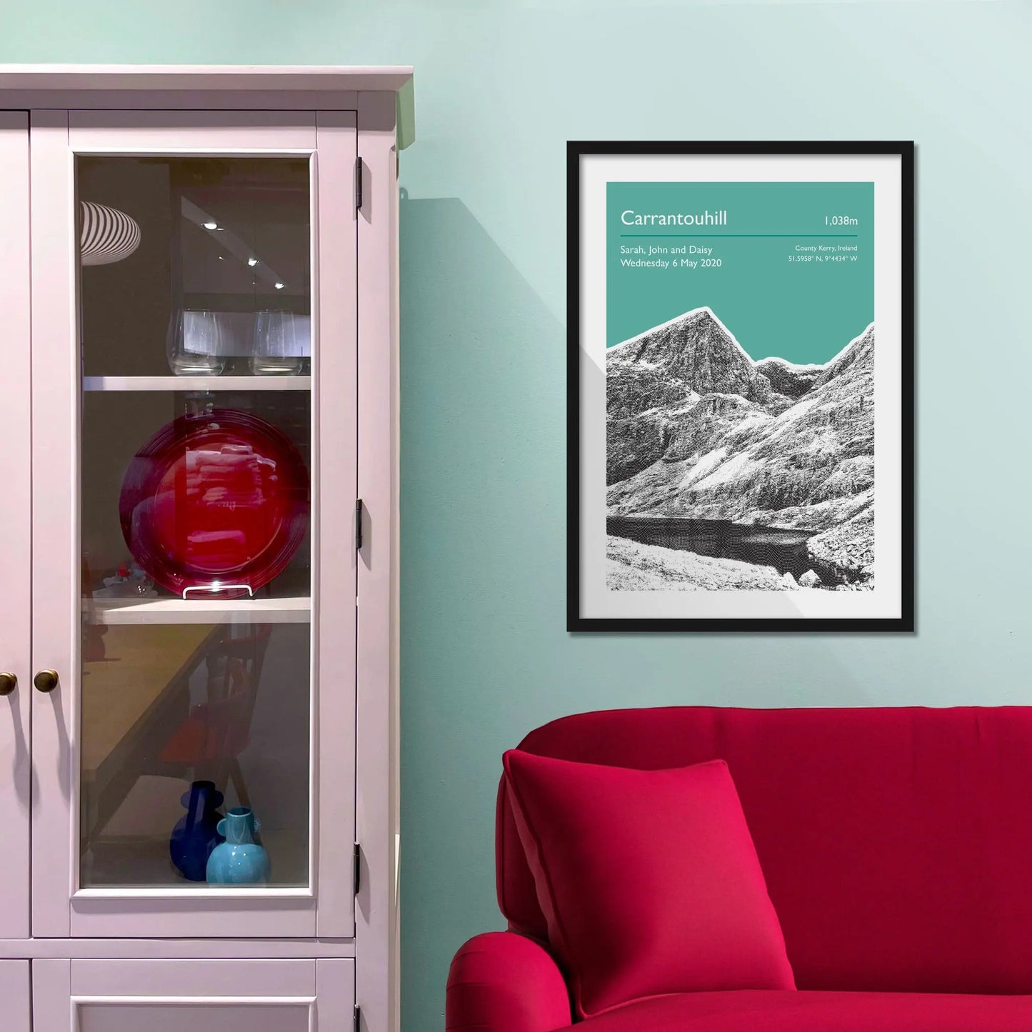 Framed picture on a baby blue wall beside pink shelving