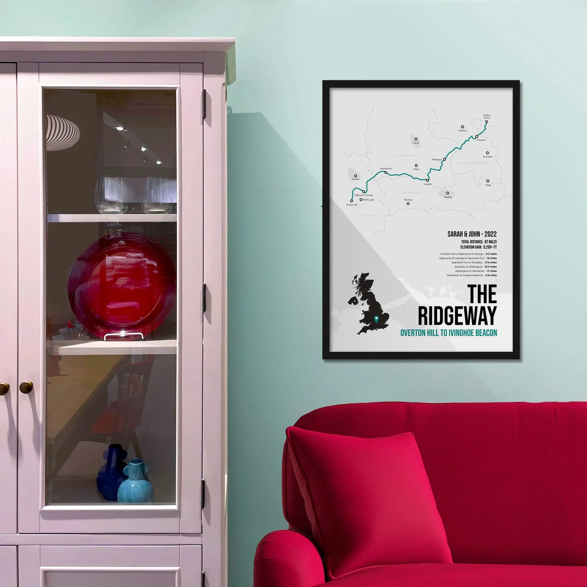 Framed picture on a baby blue wall beside pink shelving