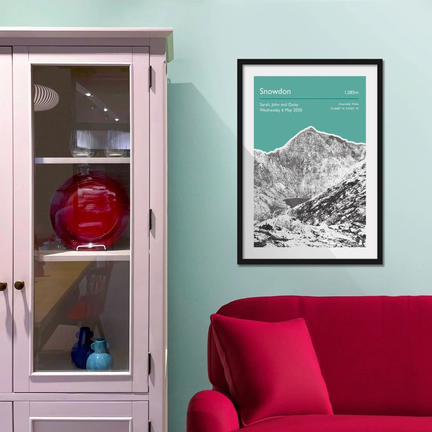 Framed picture on a baby blue wall beside pink shelving