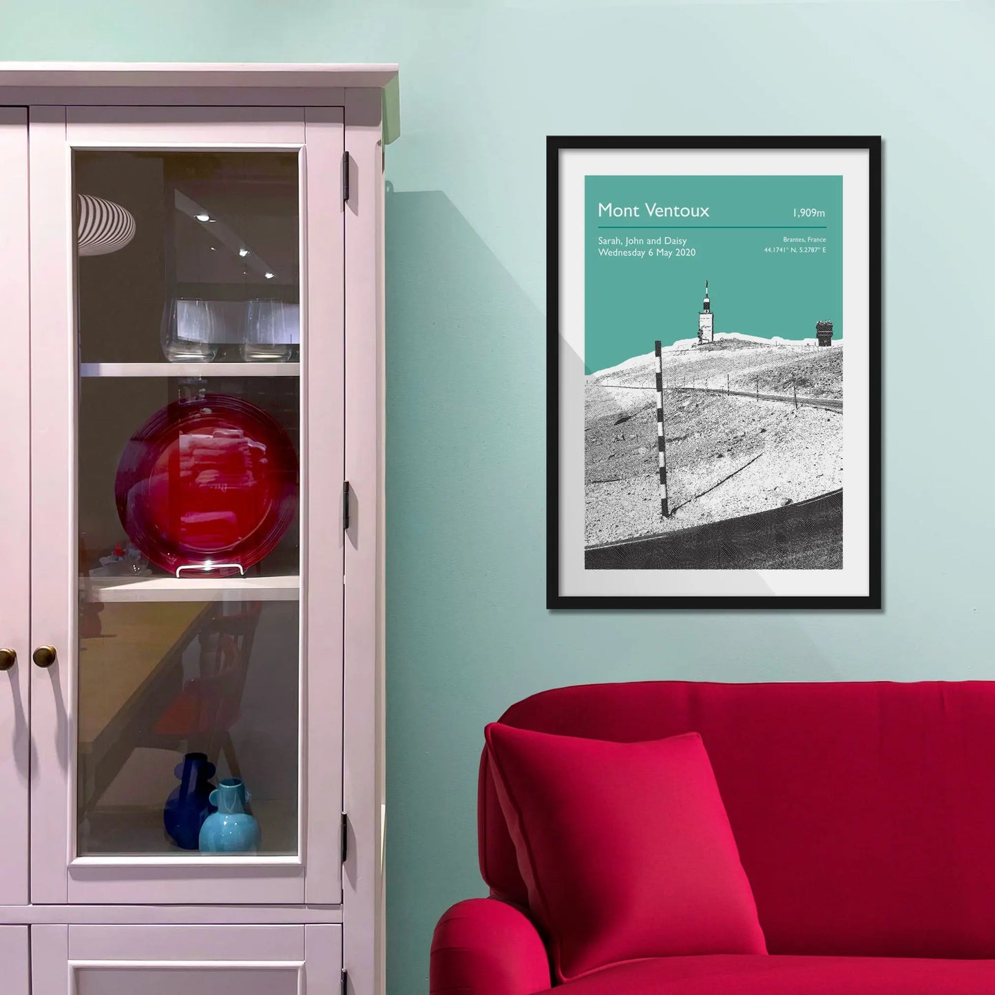 Framed picture on a baby blue wall beside pink shelving