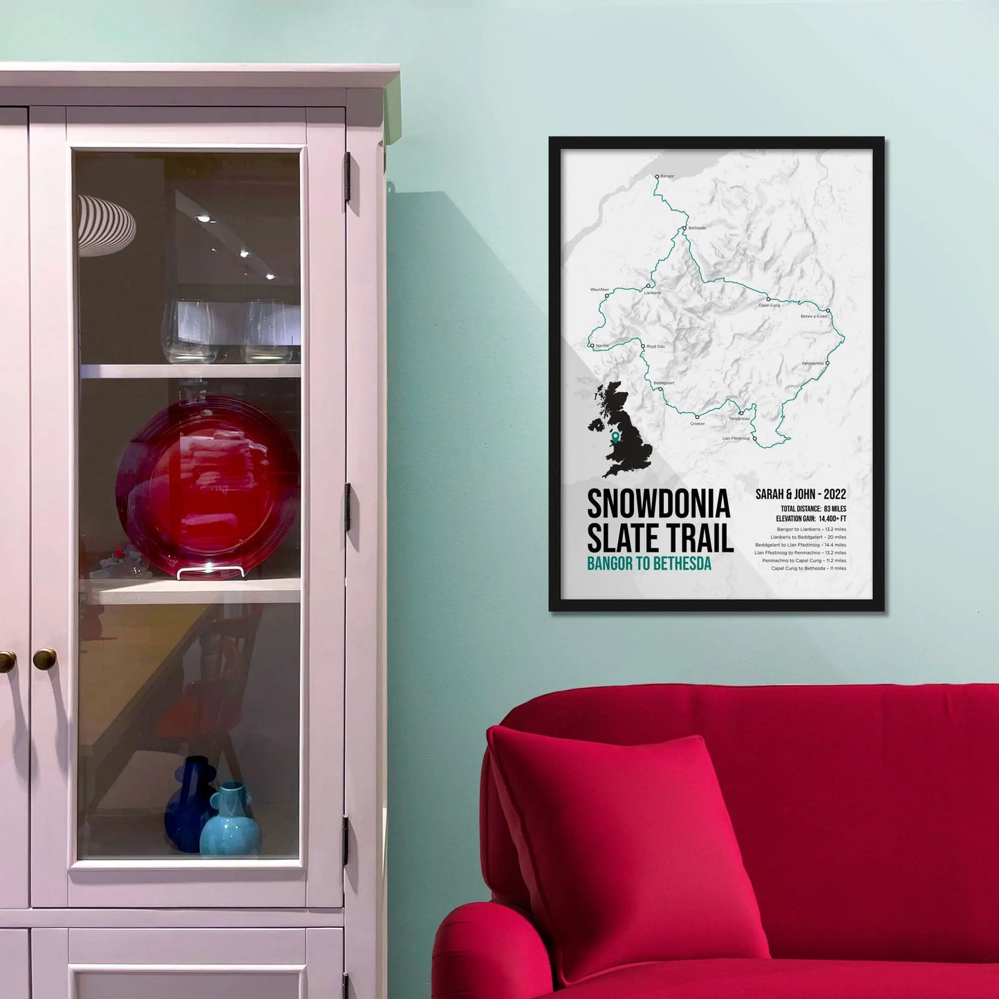Framed picture on a baby blue wall beside pink shelving