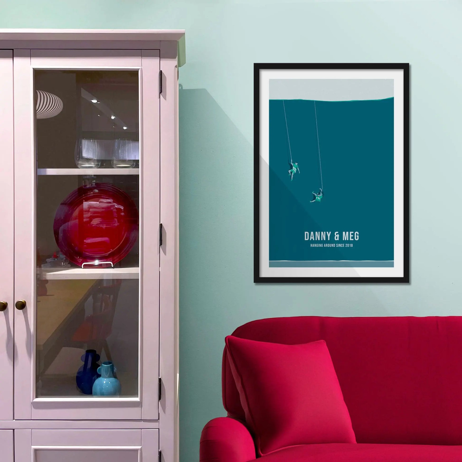 Framed print on light blue wall beside pink shelving unit.