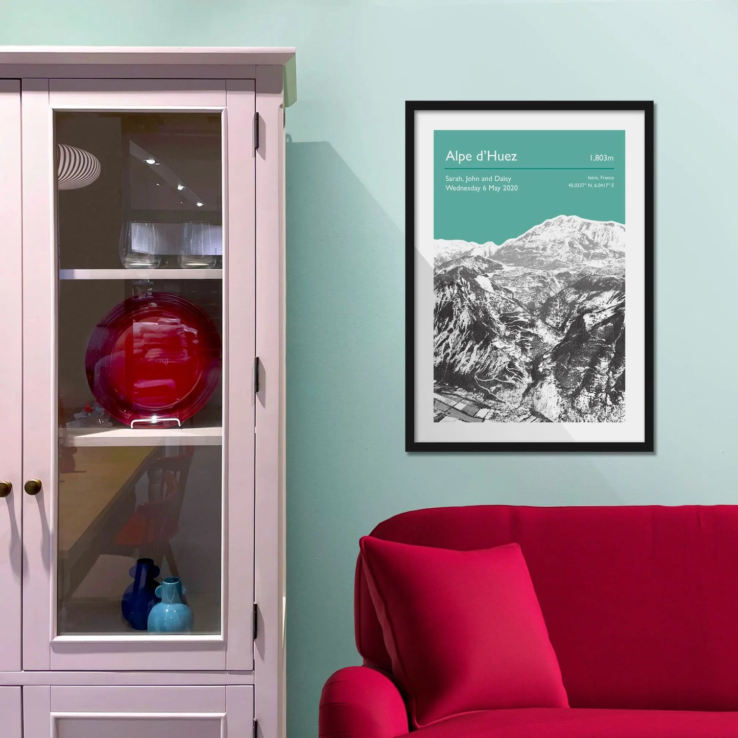 Framed picture on a baby blue wall beside pink shelving