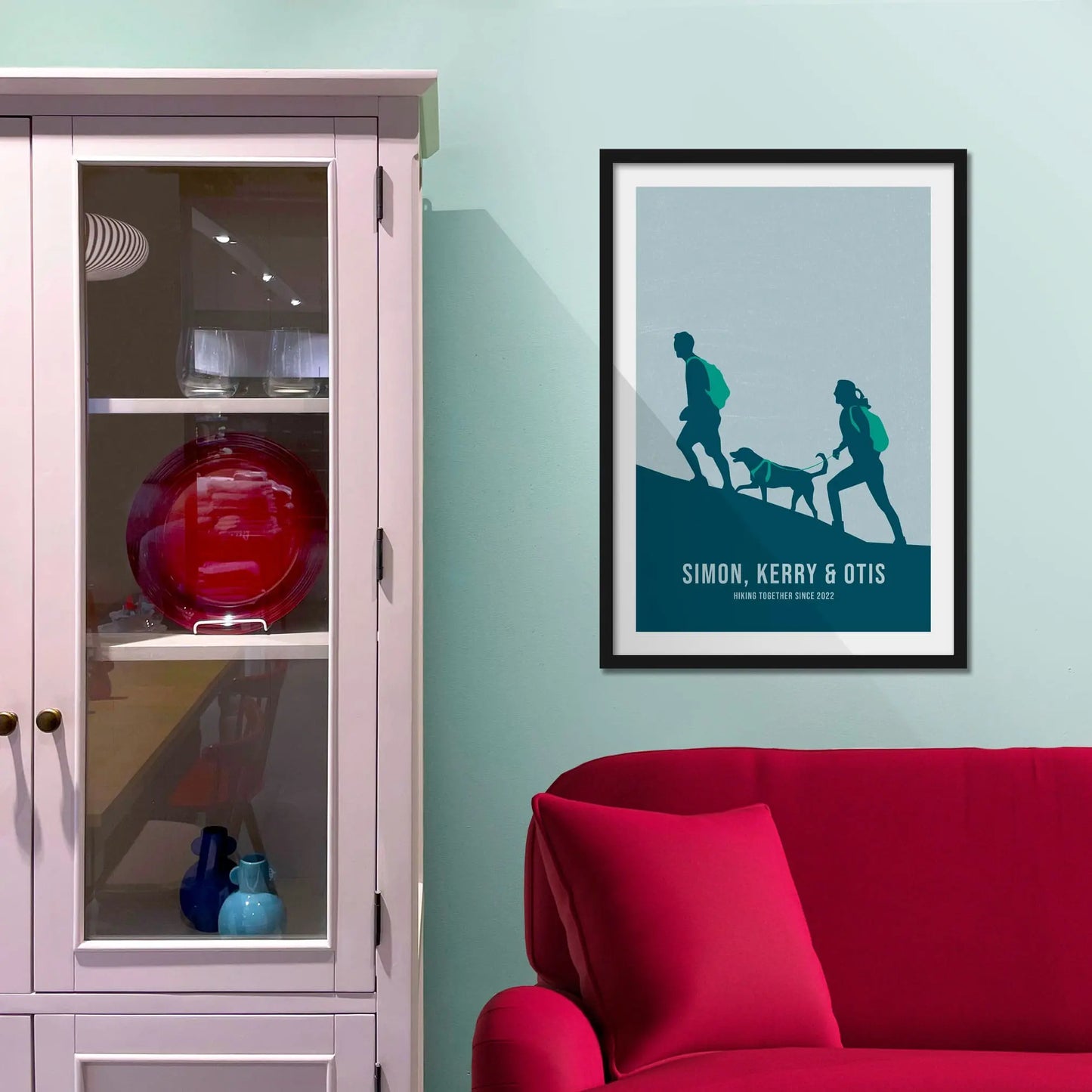 Framed print on light blue wall beside pink shelving unit.