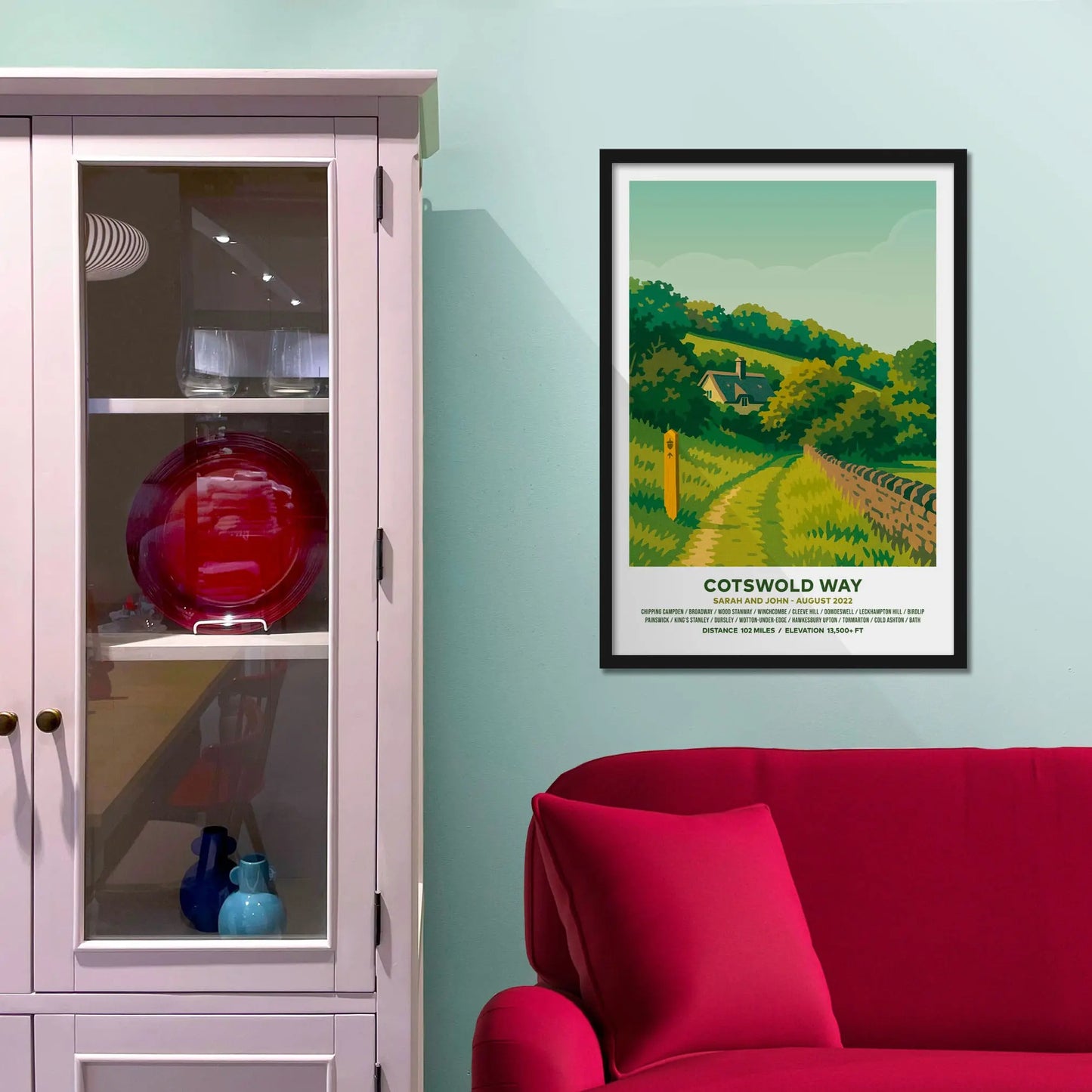 Framed picture on a baby blue wall beside pink shelving