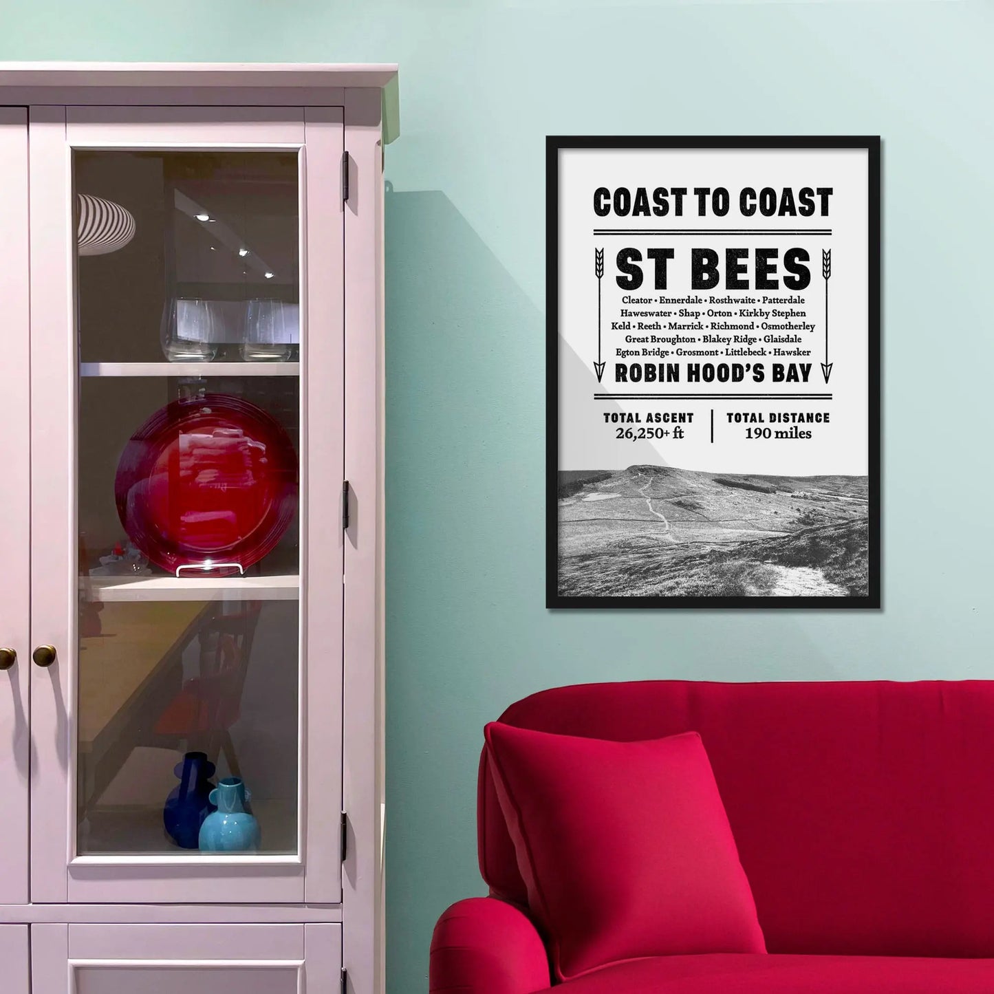 Framed picture on a baby blue wall beside pink shelving