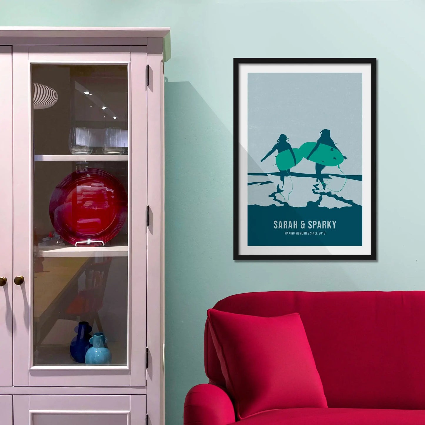 Framed picture on a baby blue wall beside pink shelving