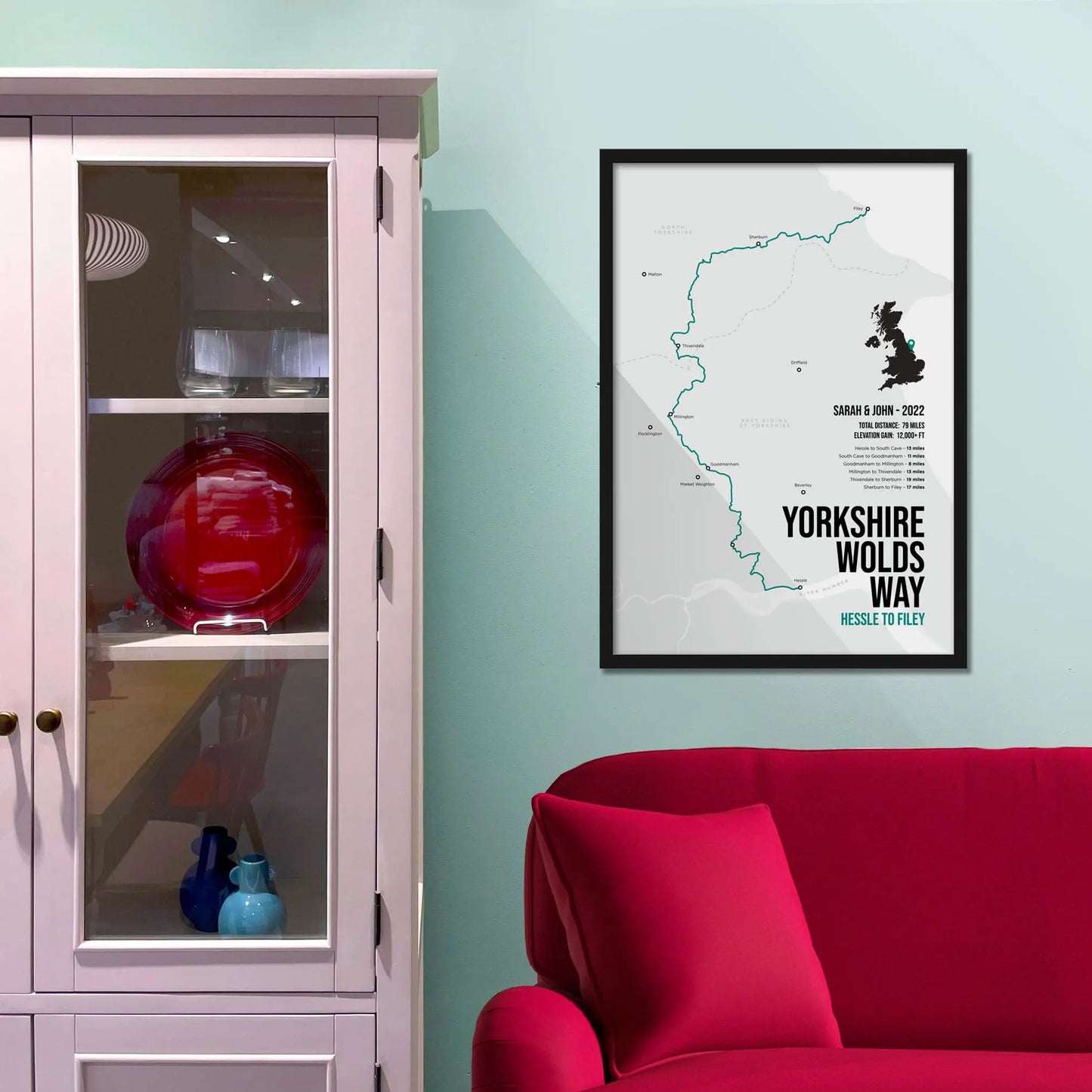 Framed print on light blue wall beside pink shelving unit.