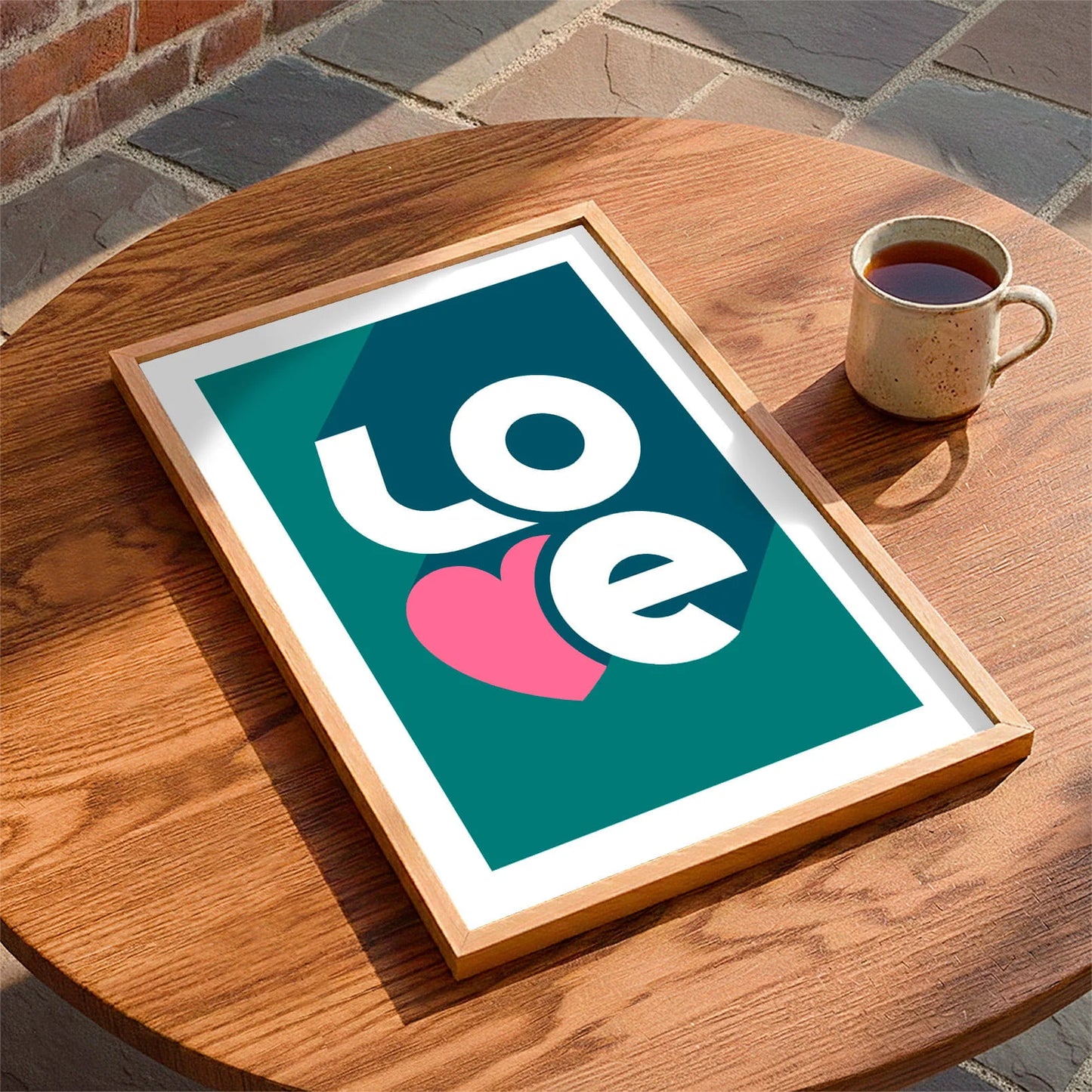 Framed print laying on a table beside a mug of tea