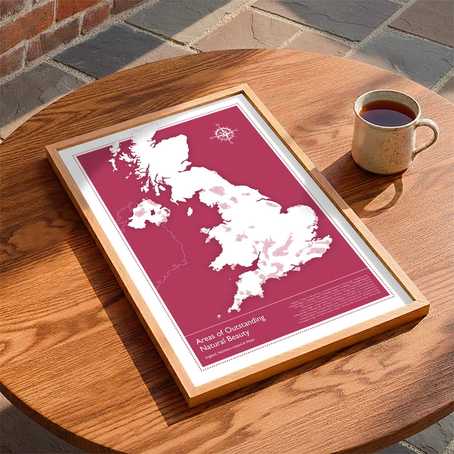 Framed print laying on a table beside a mug of tea