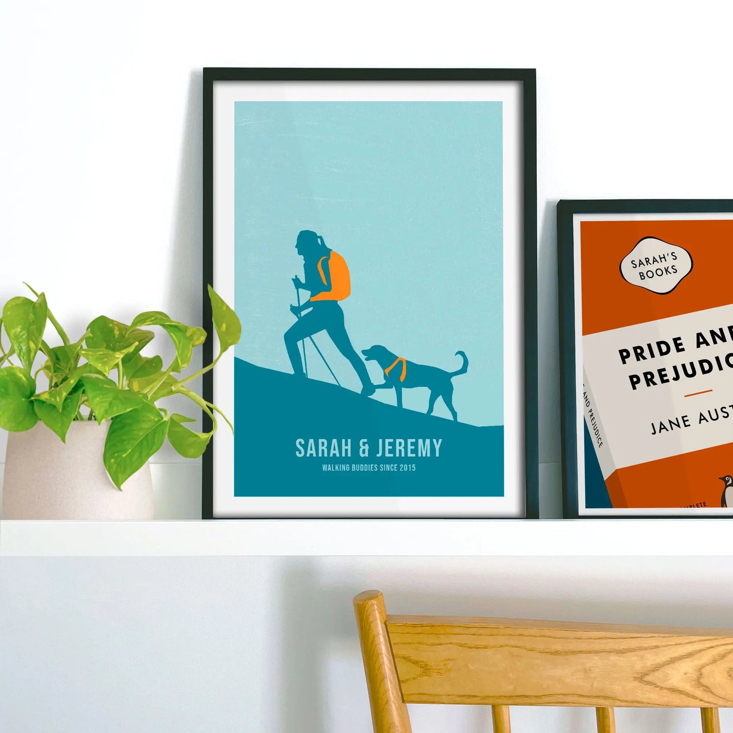 Framed print propped up on shelf beside a houseplant