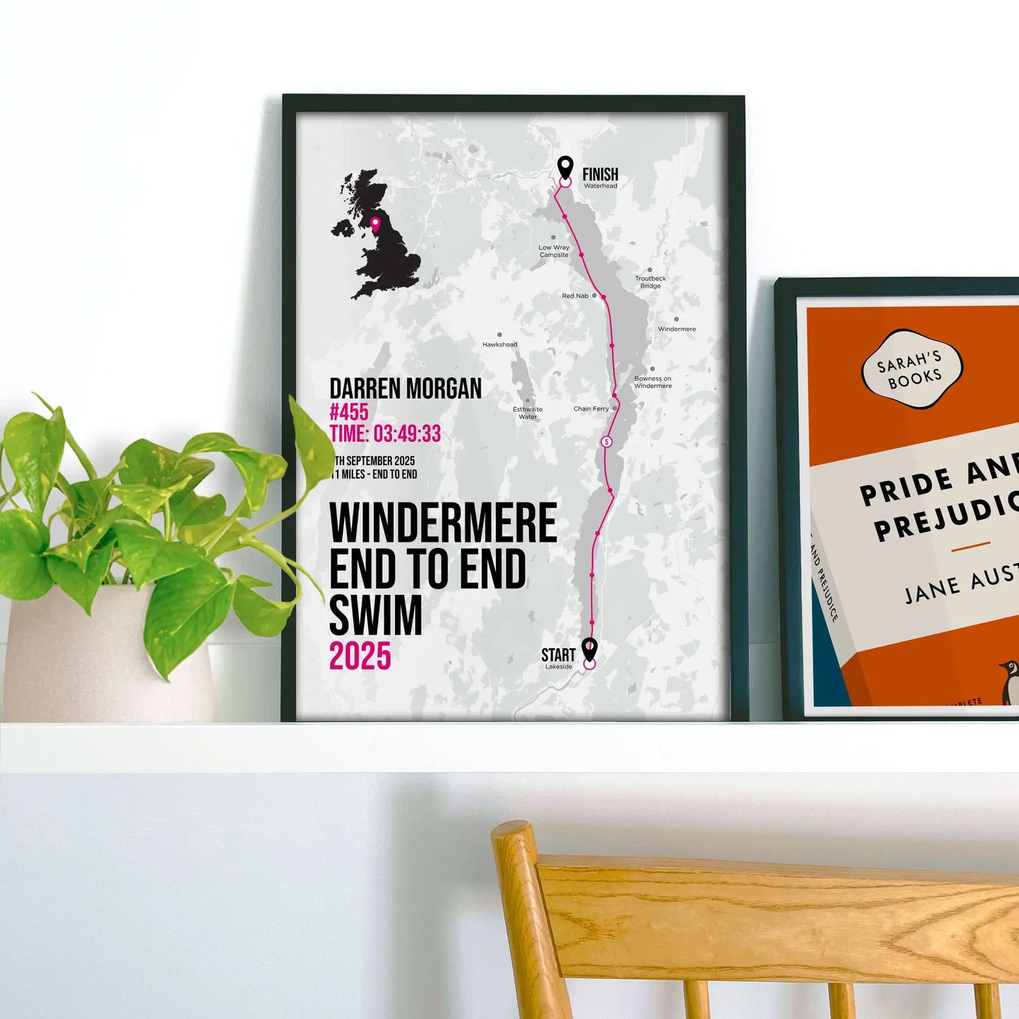 Framed print on shelf beside a houseplant and another smaller print.