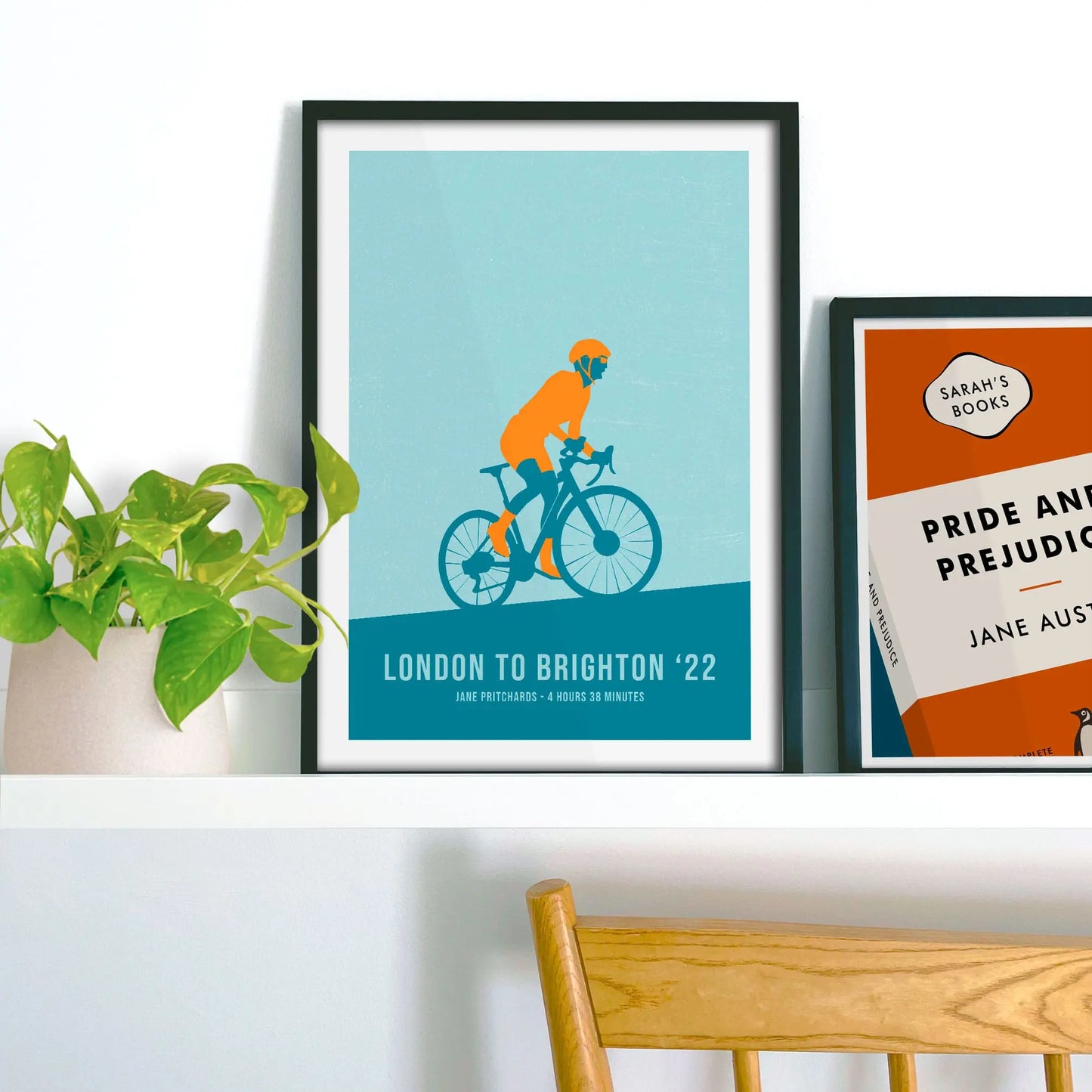 Framed print propped up on shelf beside a houseplant