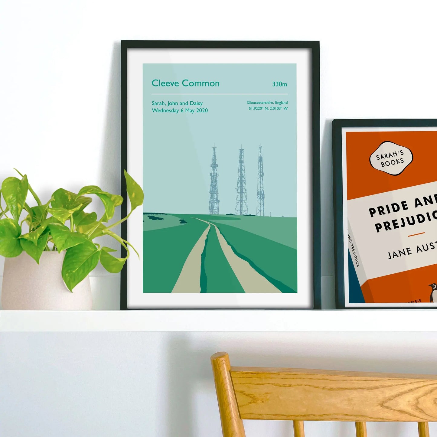 Framed picture on shelf beside a houseplant and another print.