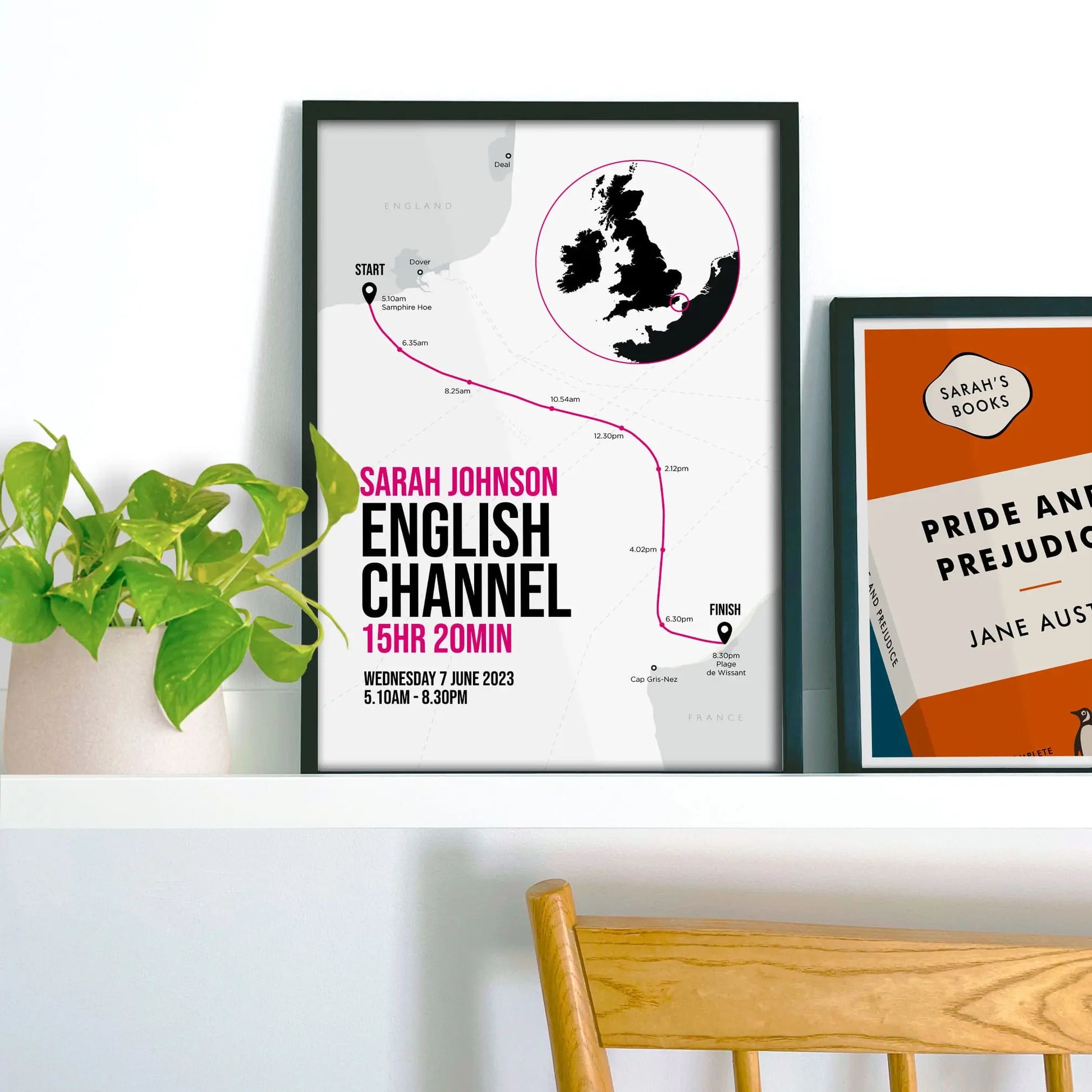Framed picture on shelf beside a houseplant and another print.