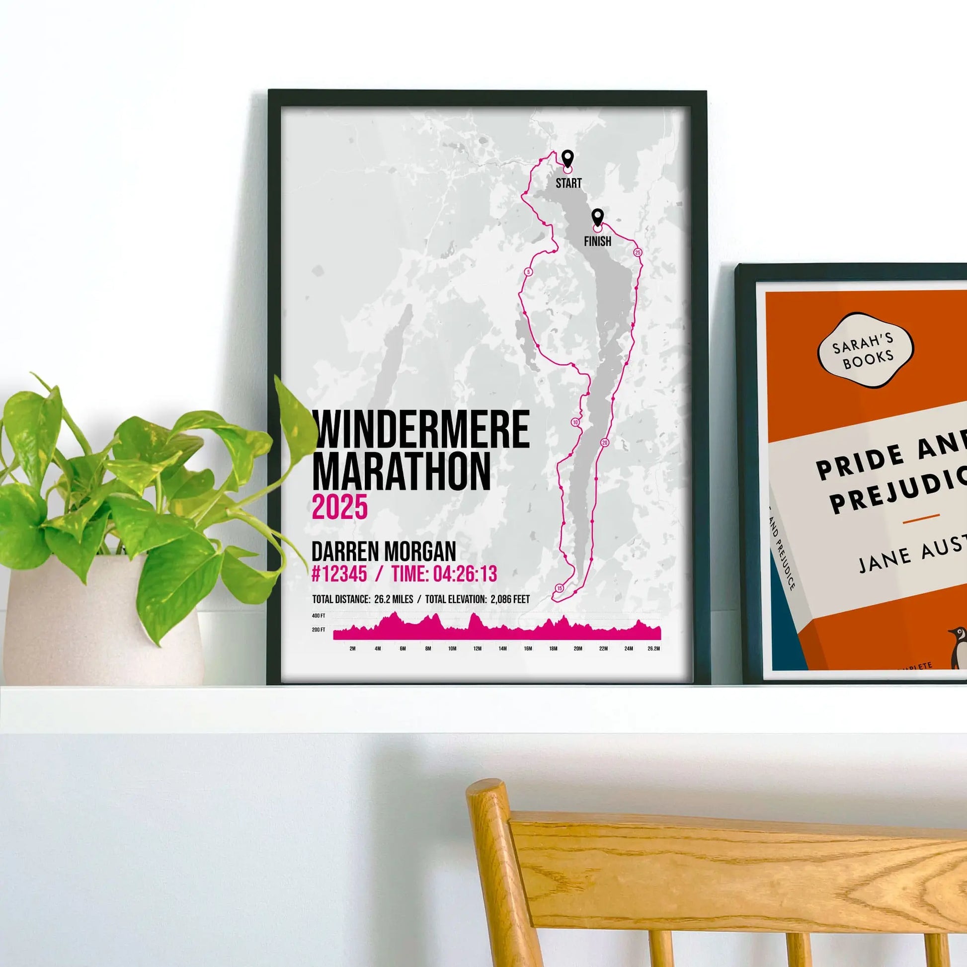 Framed print on shelf beside a houseplant and another smaller print.