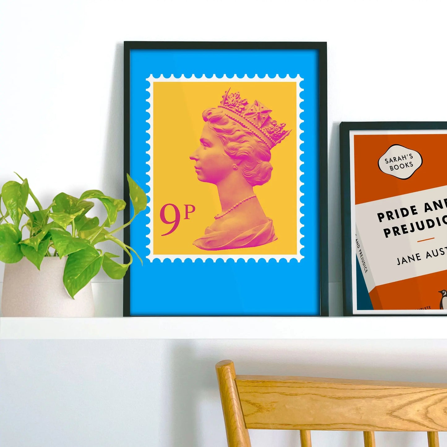Framed picture on shelf beside a houseplant and another print.
