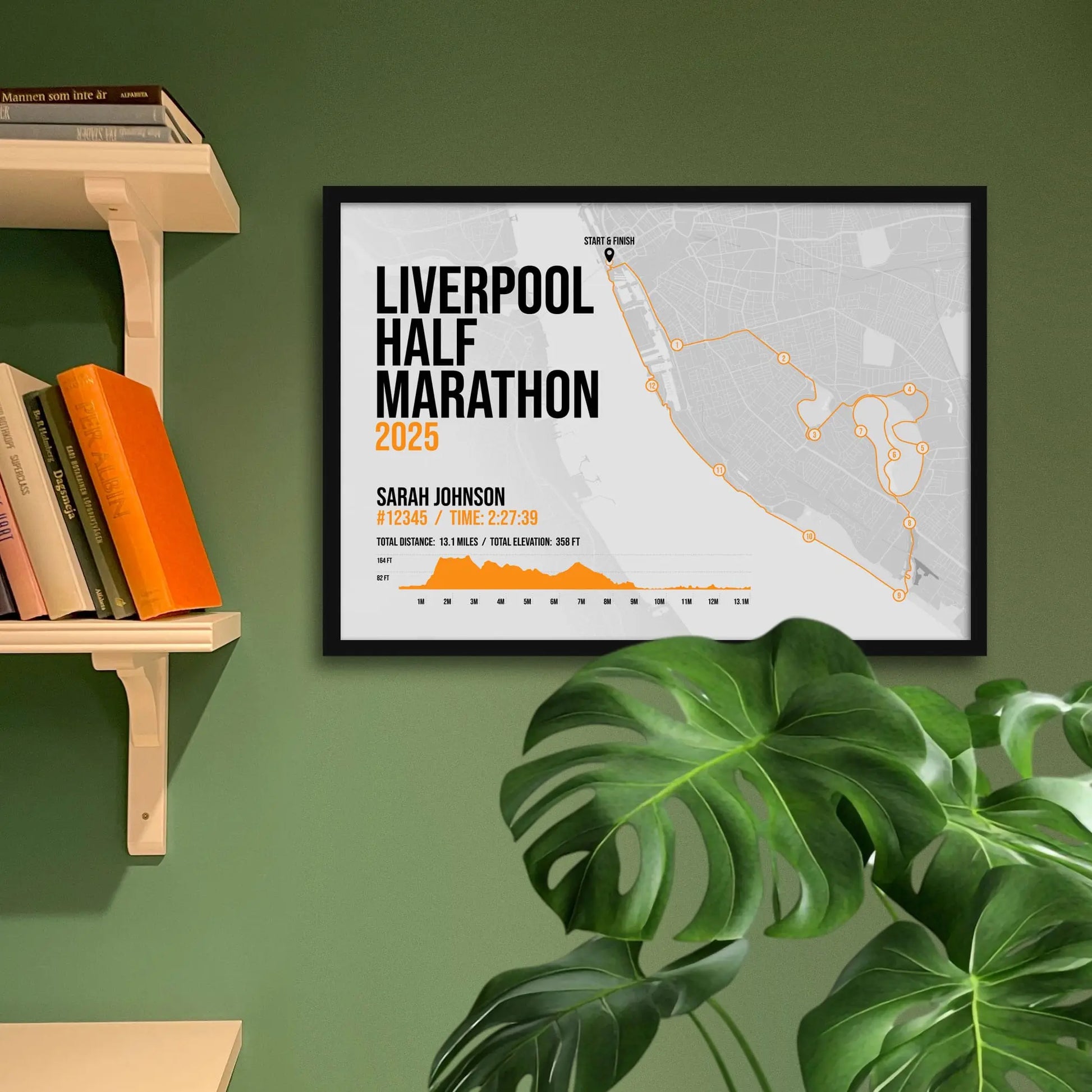 Print framed and in a black frame on a green wall beside some shelves