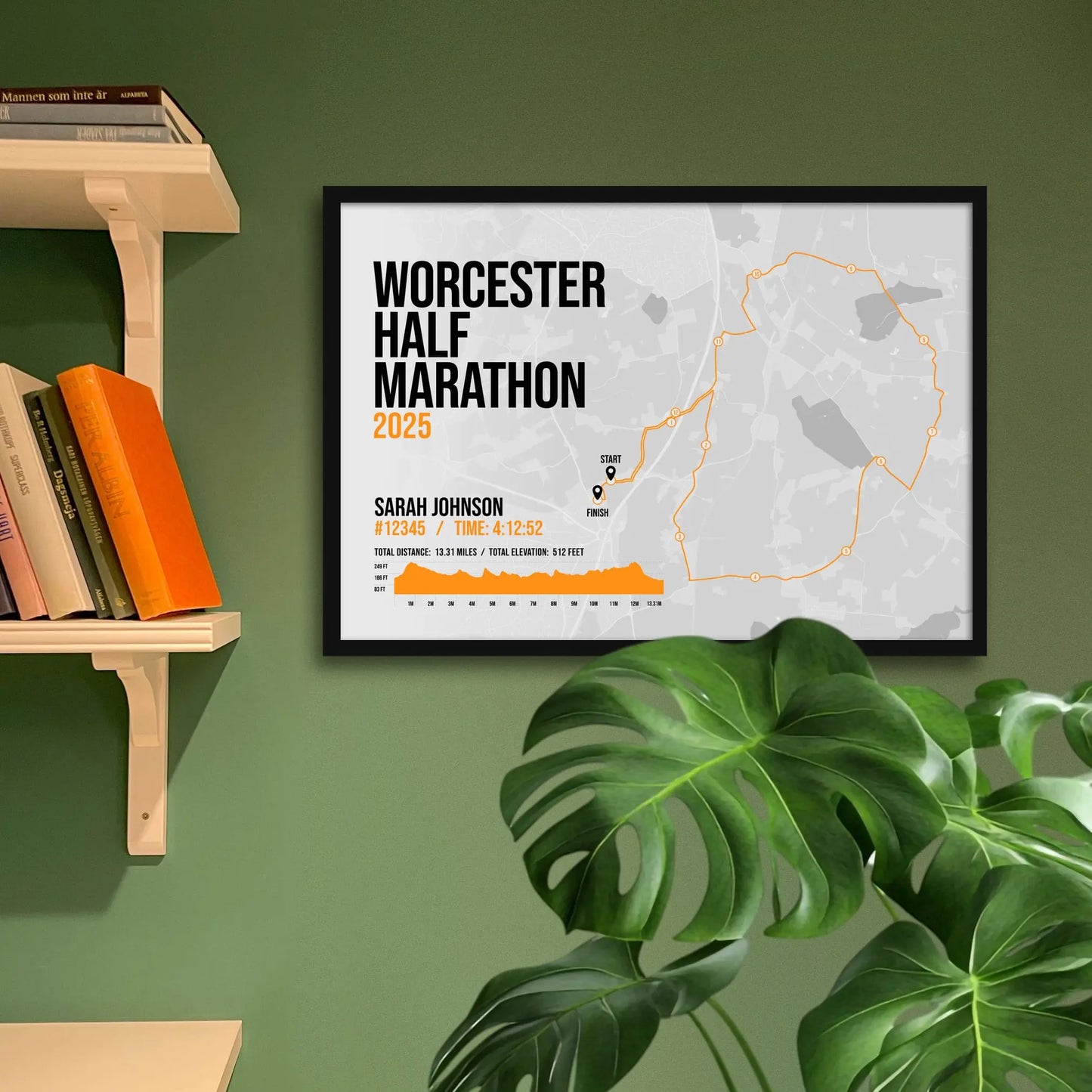 Framed print on green wall beside shelving and houseplant