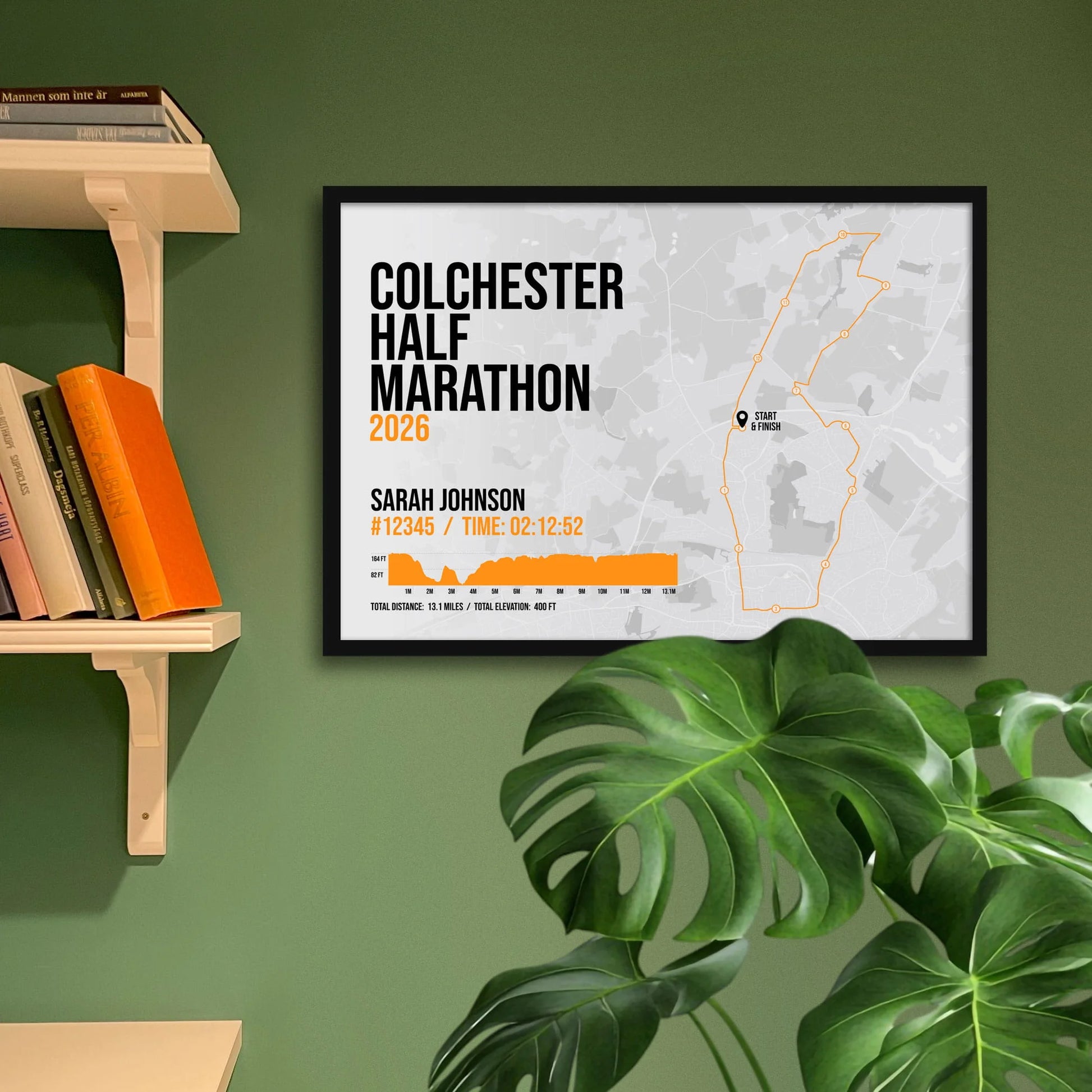 Print framed and in a black frame on a green wall beside some shelves