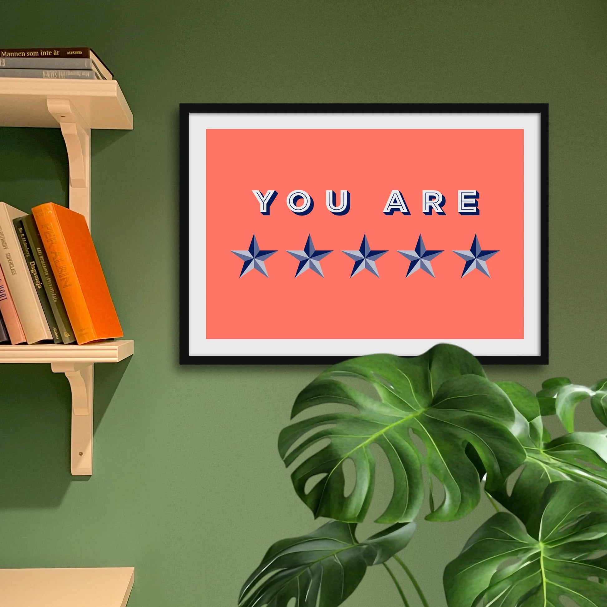 Framed print on green wall above a houseplant