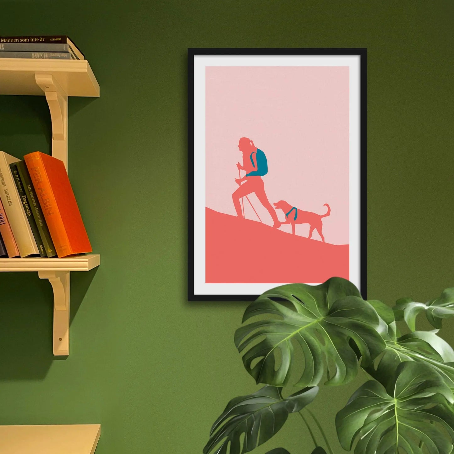 Framed print on green wall beside shelves behind houseplant.