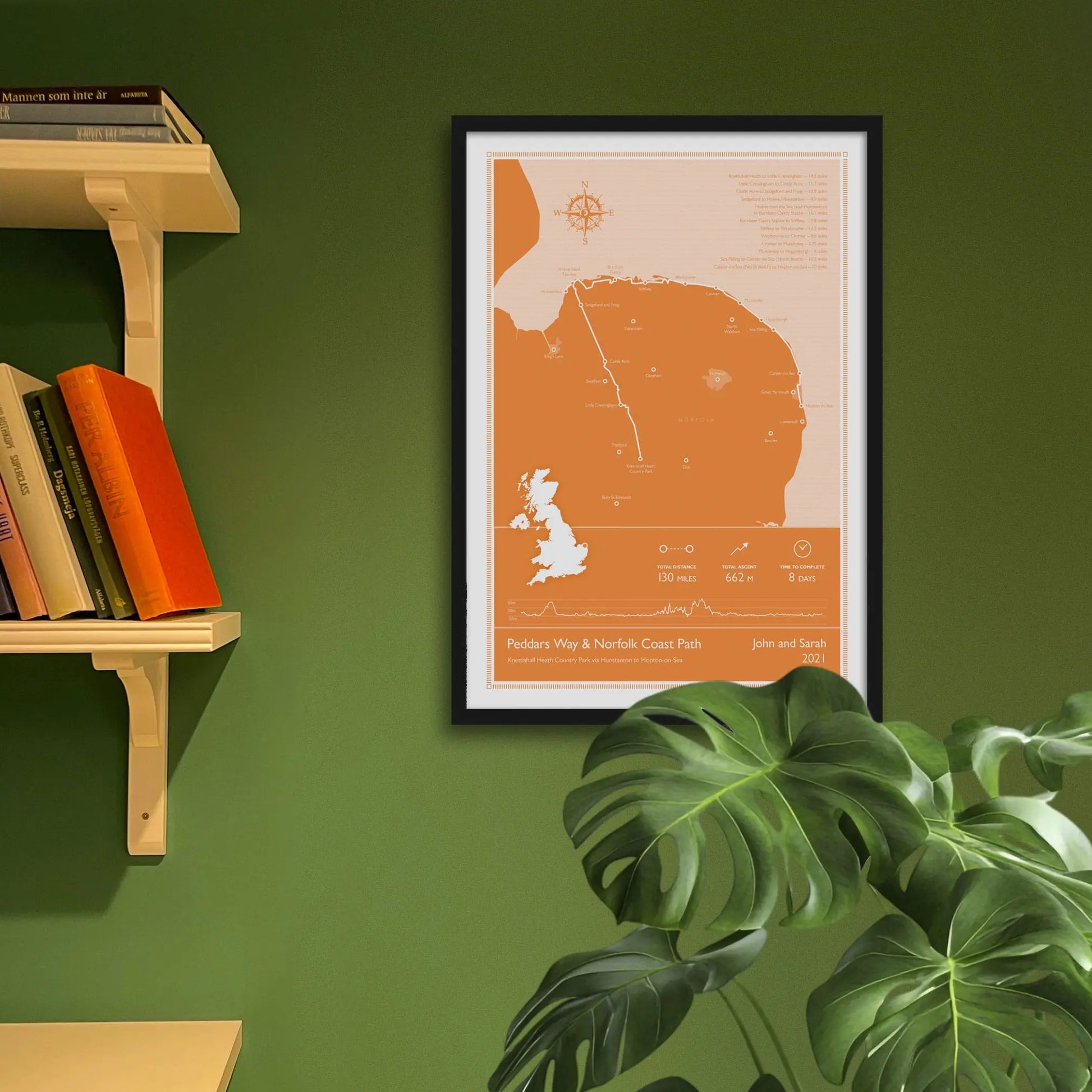 Framed art print on a green wall beside shelves.